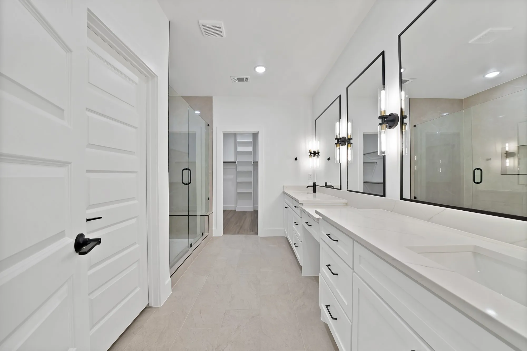 Dual vanities with quartz countertops, custom cabinetry, large framed mirrors, and contemporary sconce lighting