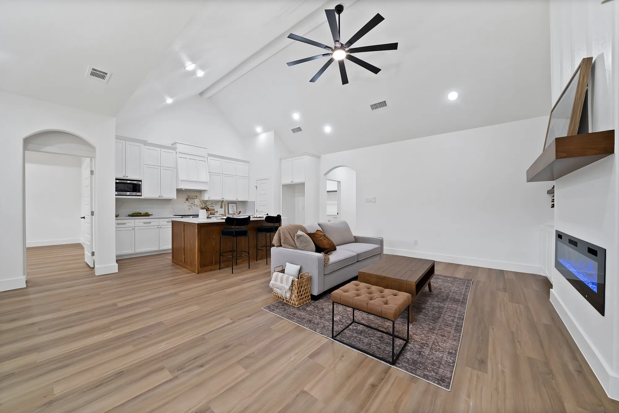 Open-concept living area featuring high vaulted ceilings with a contemporary ceiling fan, wood-finish flooring, and recessed lighting