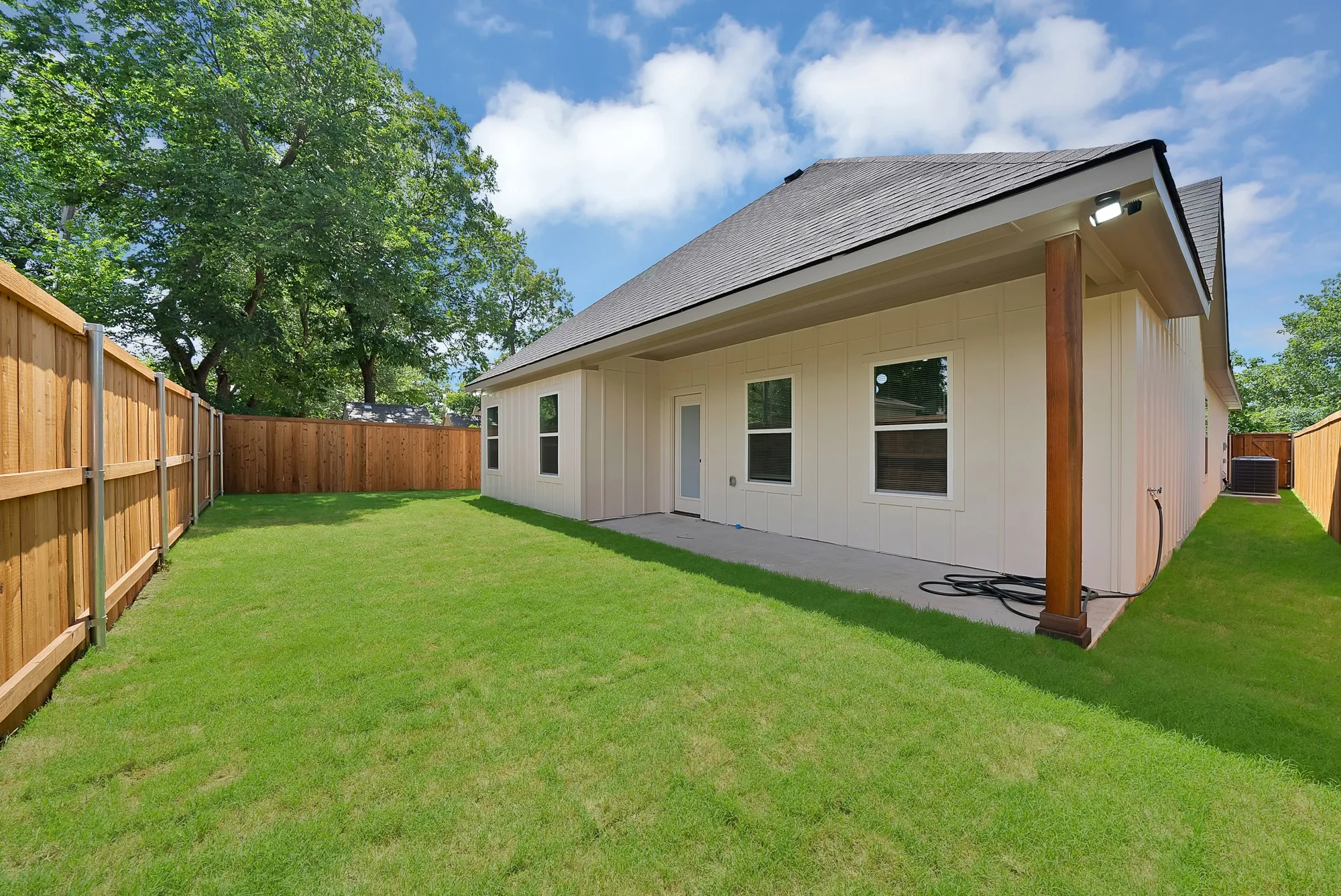 Private backyard featuring a concrete patio, wood privacy fencing, and a manicured lawn