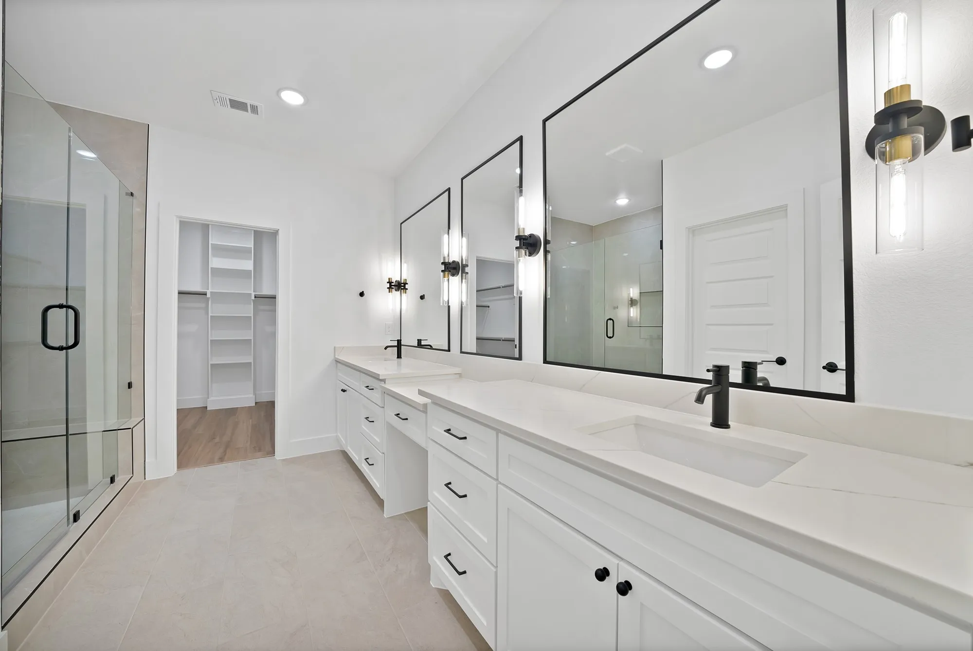Bathroom featuring a dual vanity with white cabinetry, integrated sinks, and matte black fixtures