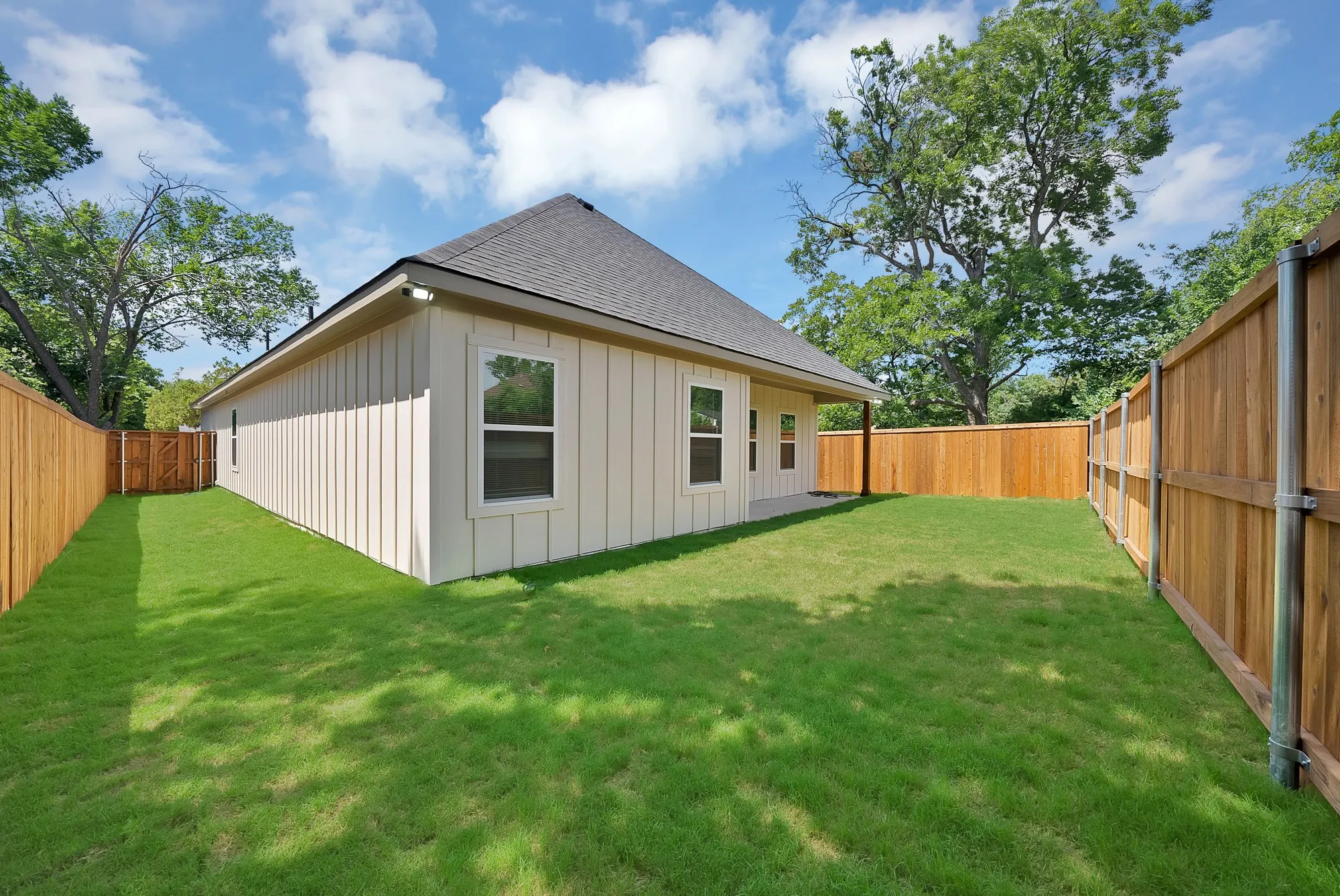 Manicured lawn surrounding a board and batten exterior with multiple windows