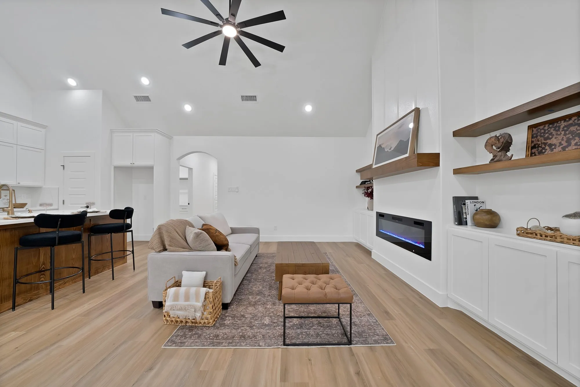 Open-concept living area with wood-finish flooring, a vaulted ceiling, and recessed lighting