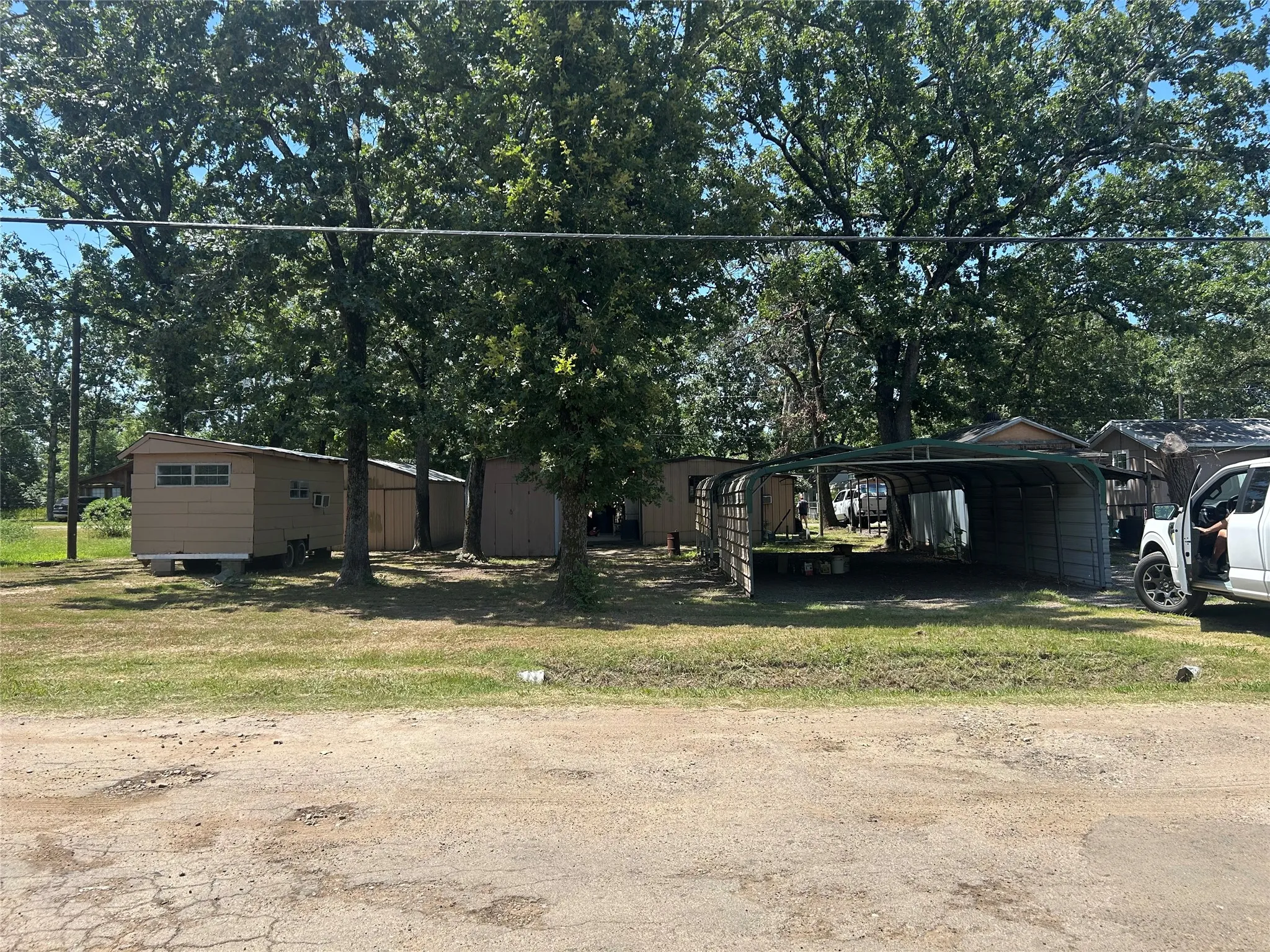 Back of property showing carports, position of single wide.  Trailer on left will be removed prior to sell.