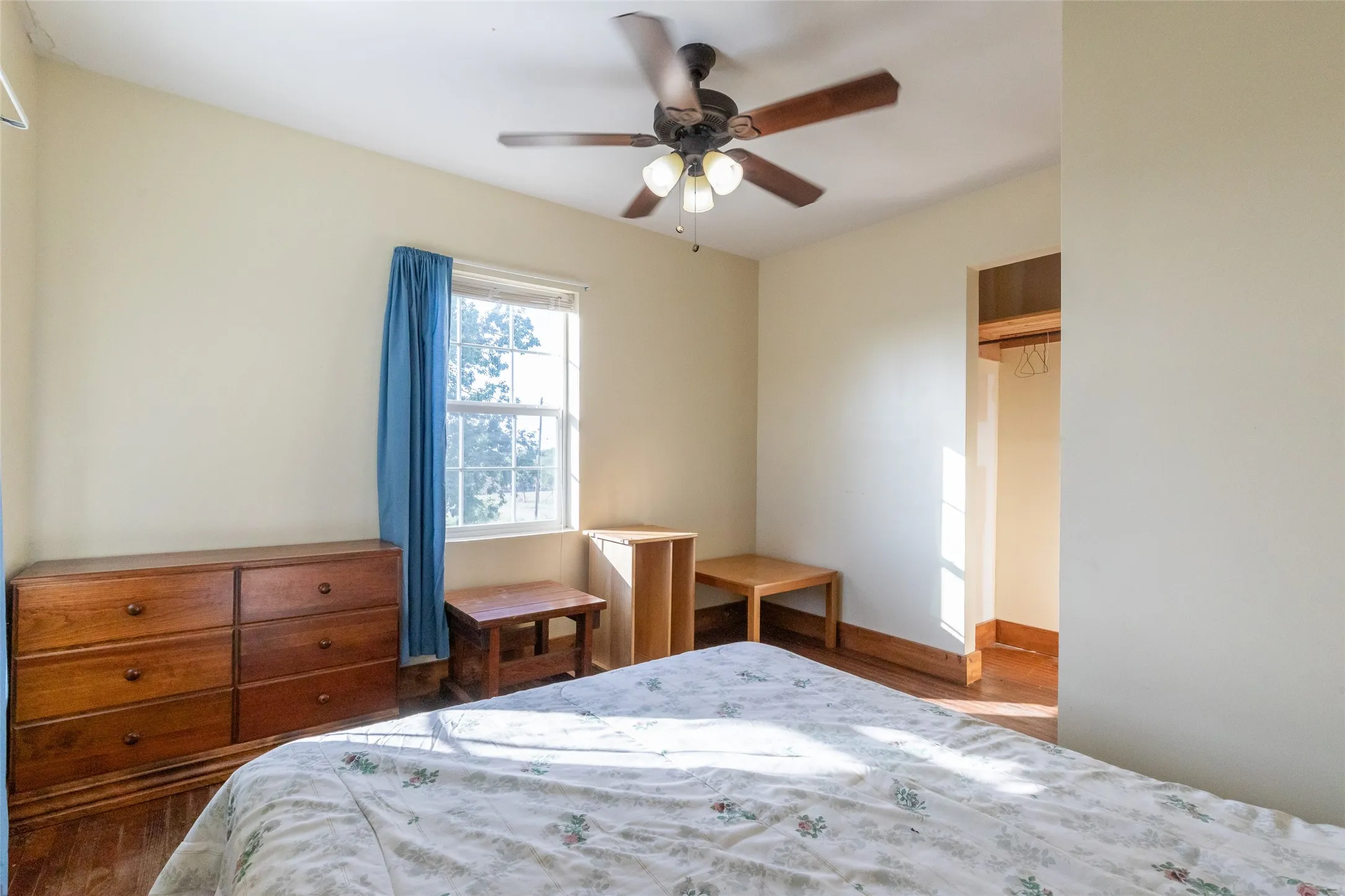 Room featuring wood-finish flooring, a window with natural light, and a ceiling fan with integrated lighting
