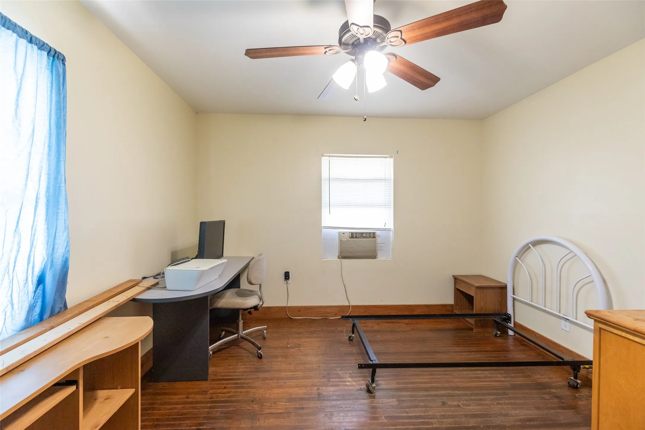 Room featuring wood-finish flooring, a ceiling fan with light fixture, and neutral painted walls