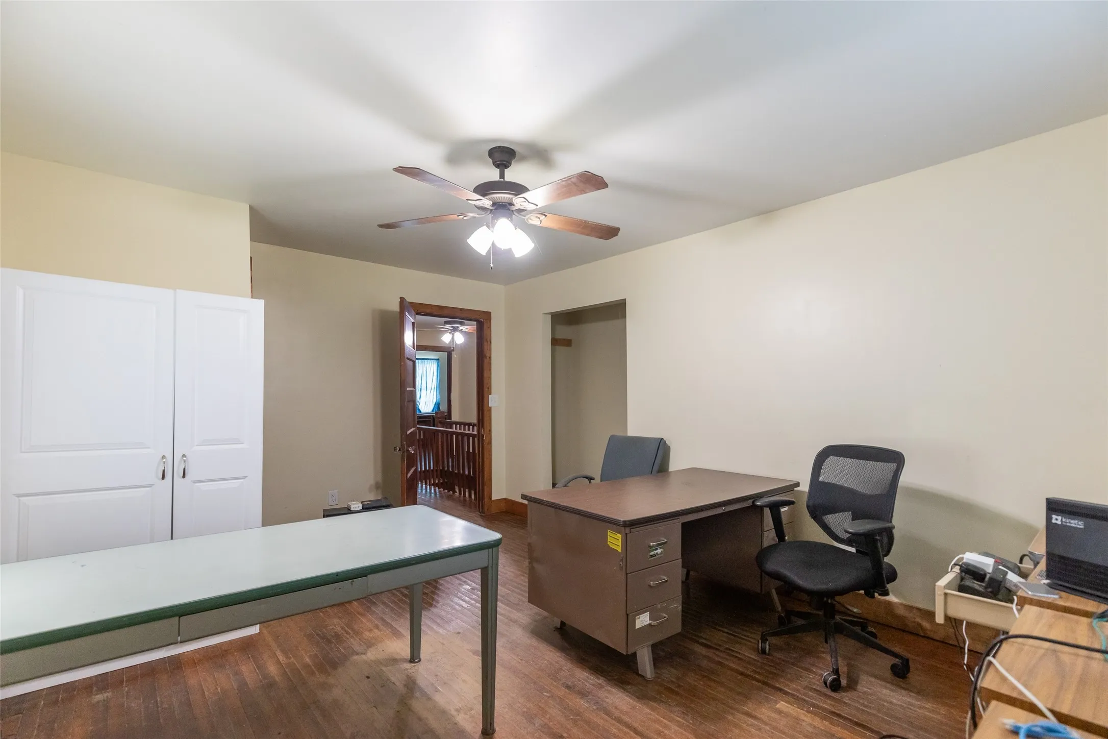Spacious room featuring wood-finish flooring, a ceiling fan with integrated lighting, and neutral-toned walls
