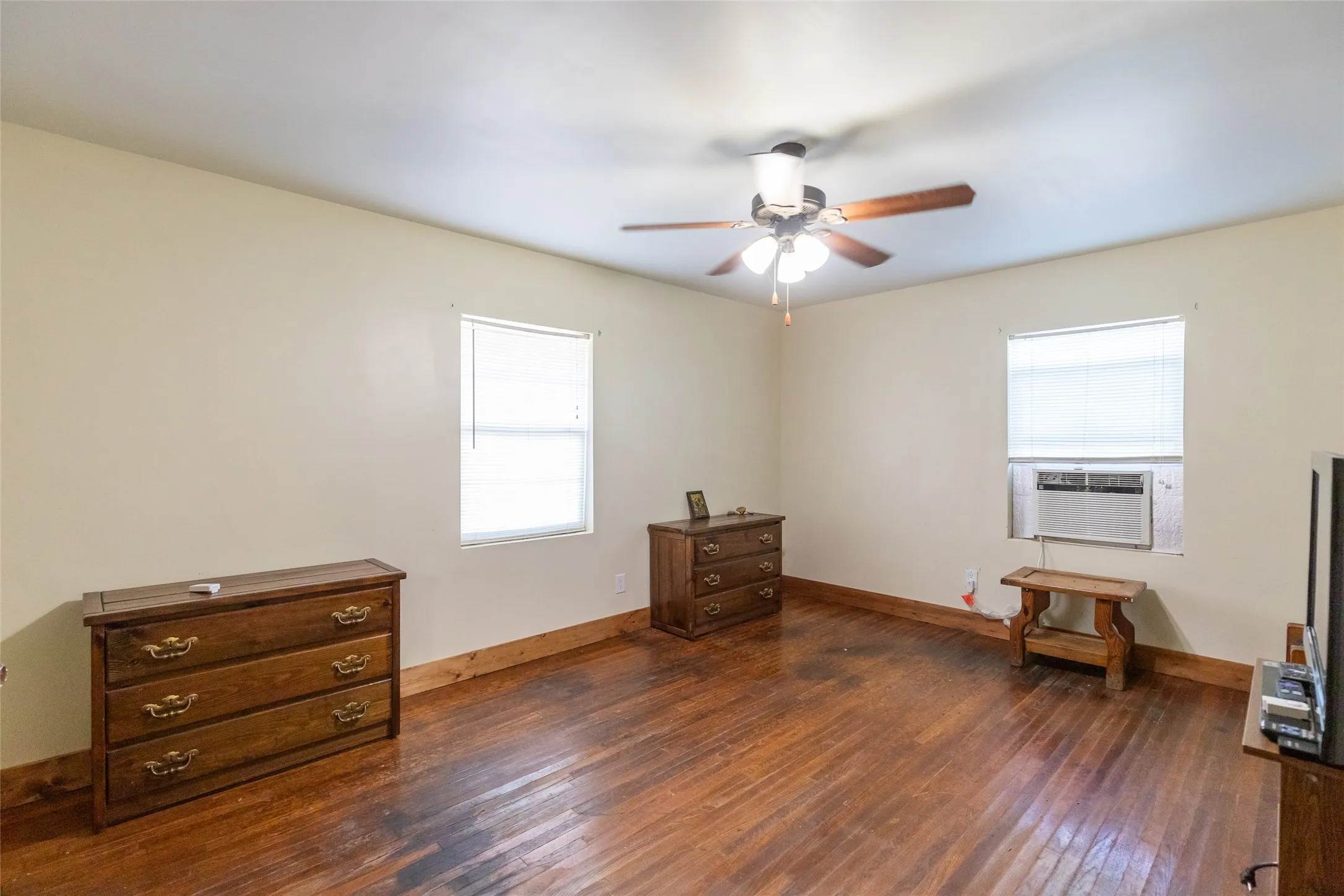 Spacious interior featuring wood-finish flooring, light-toned walls, and a ceiling fan with integrated lighting