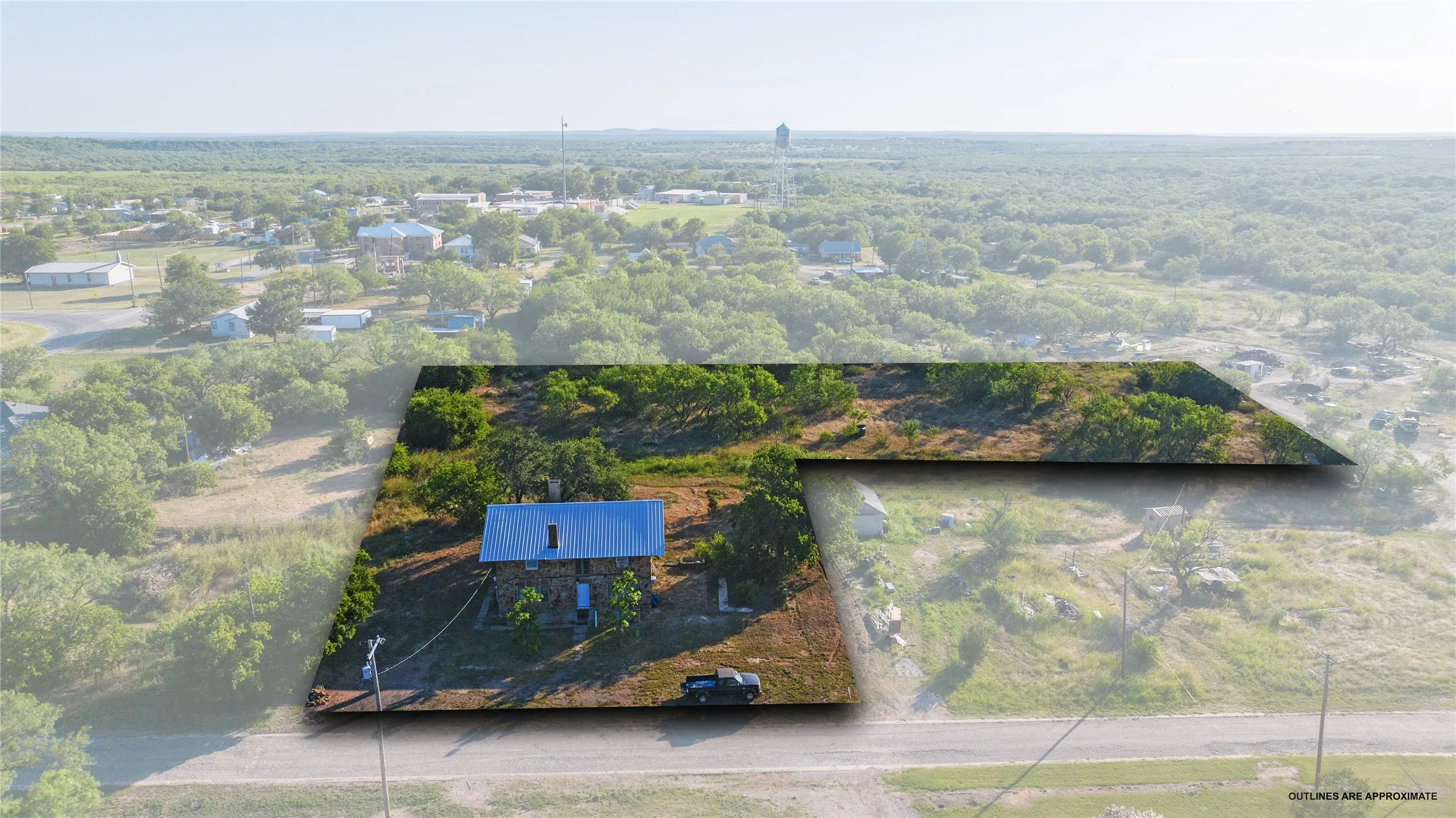 Aerial property overview featuring a single-story residence with a light blue metal roof and stone exterior