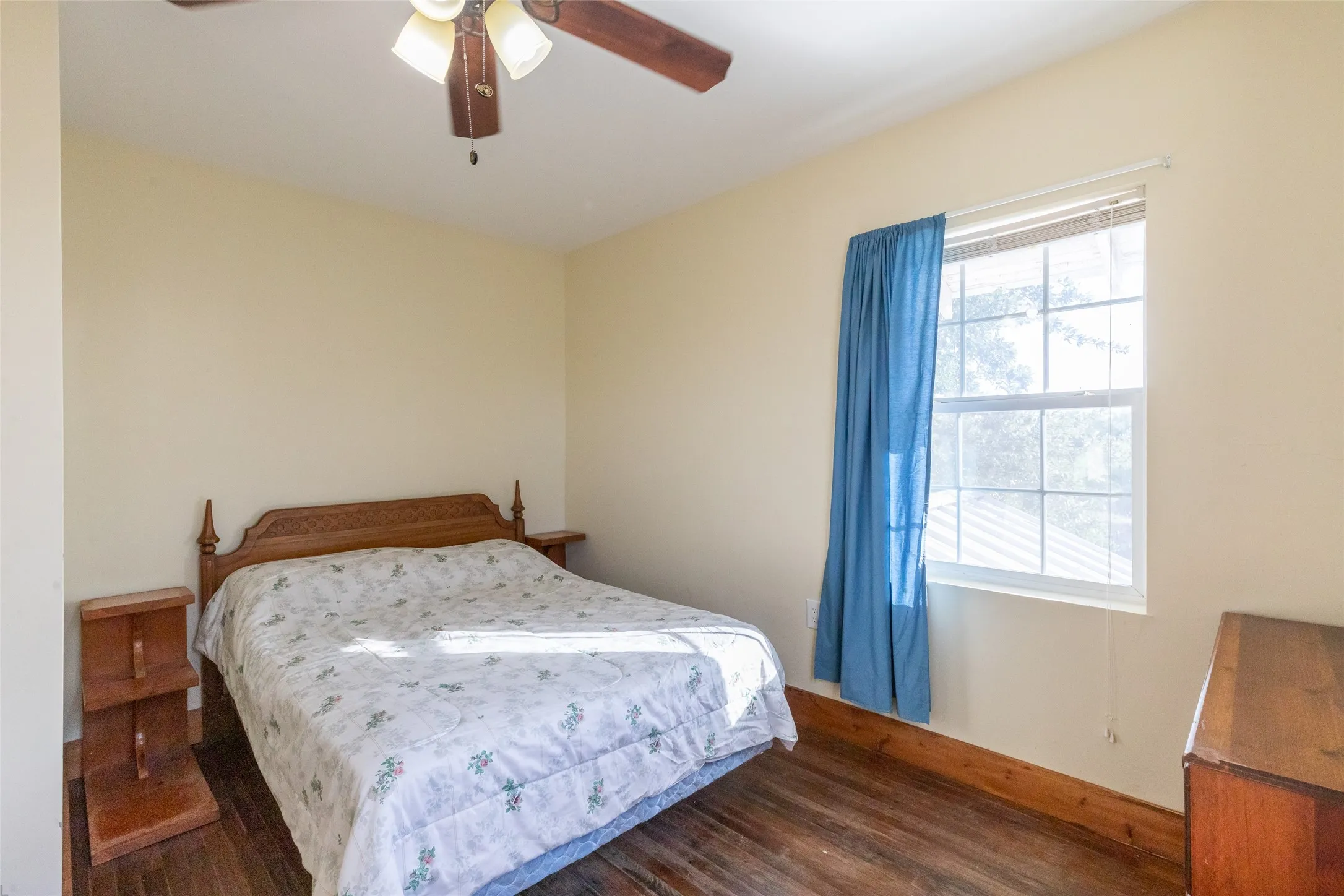 Bedroom featuring wood-finish flooring, a ceiling fan with integrated lighting, and a window providing natural illumination