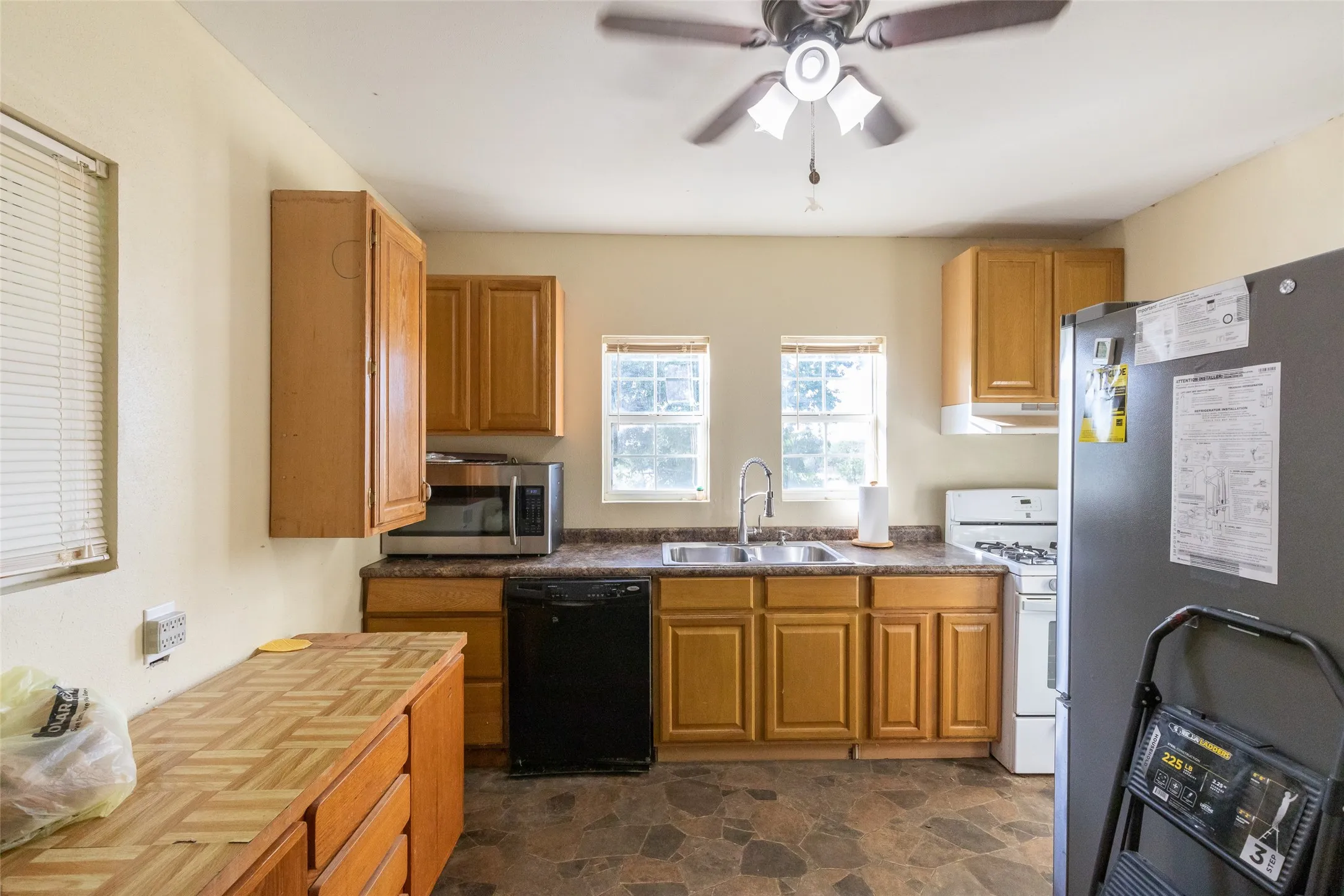 Kitchen featuring wood-finish cabinetry, a double basin sink, and an overhead ceiling fan with lighting