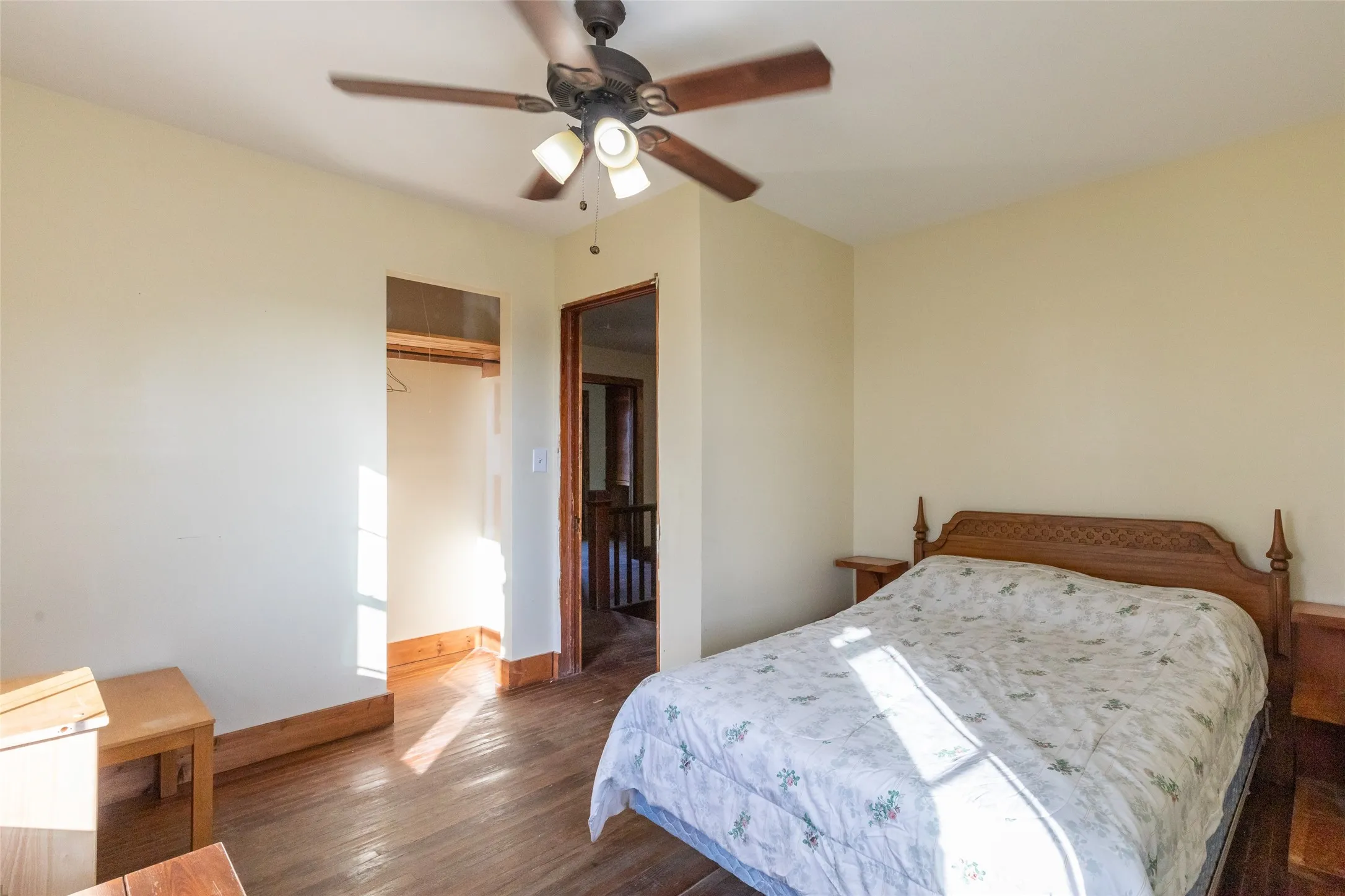 Bedroom featuring wood-finish flooring, a ceiling fan with integrated lighting, and a closet with a wood trim opening