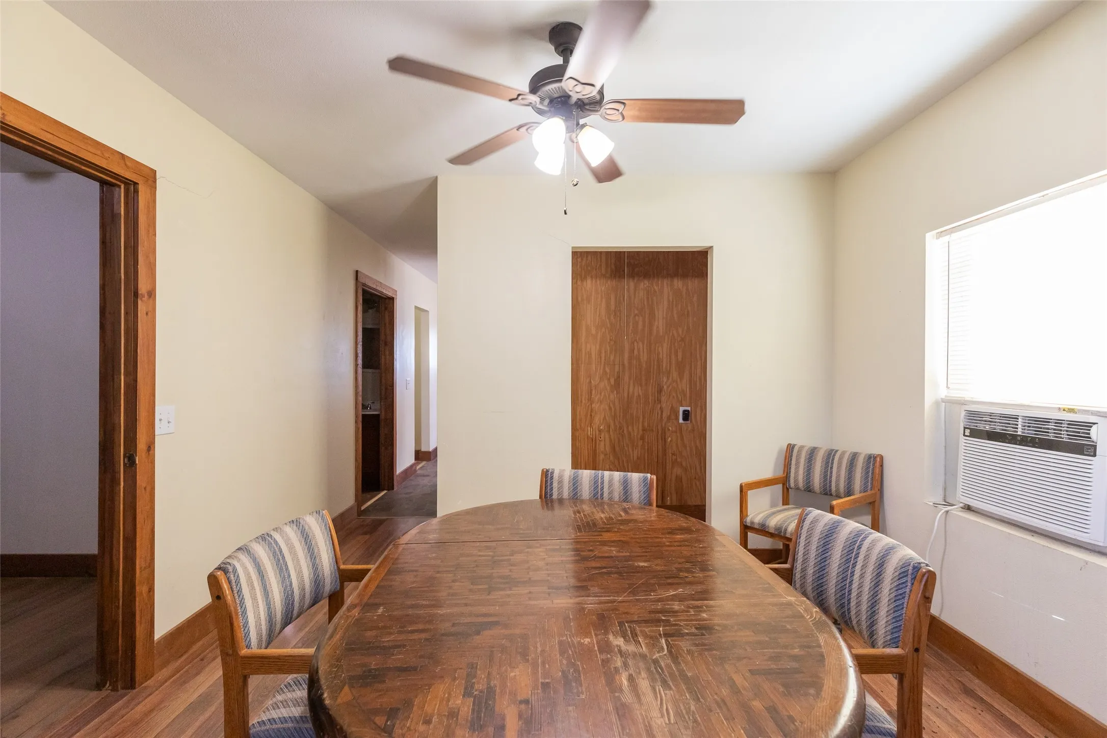 Interior space featuring wood-finish flooring, light-toned walls, and a ceiling fan with integrated lighting