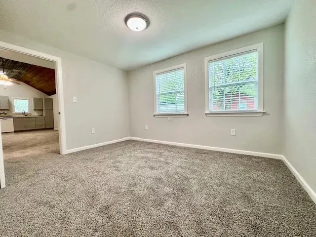 Spacious room featuring neutral grey walls and new grey carpeting