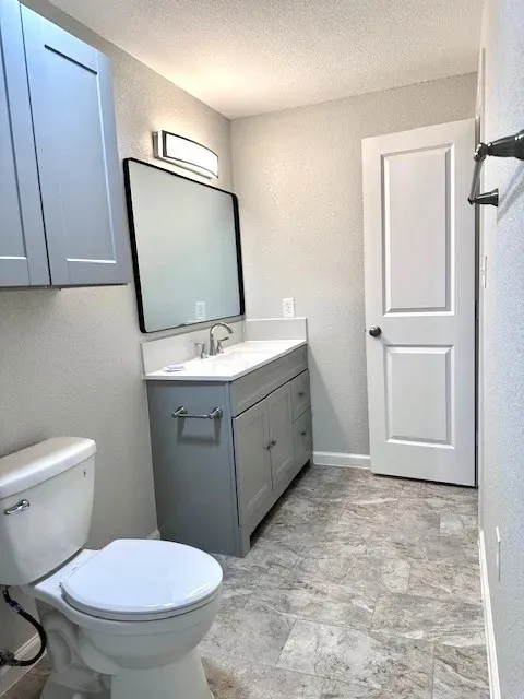 Contemporary bathroom featuring a grey vanity with a white countertop and integrated sink, a rectangular framed mirror, and a modern vanity light fixture
