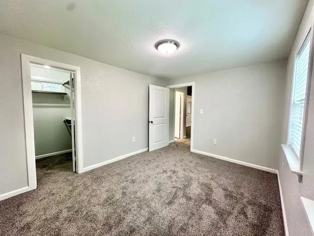 Room featuring neutral wall tones and dark-toned carpeting