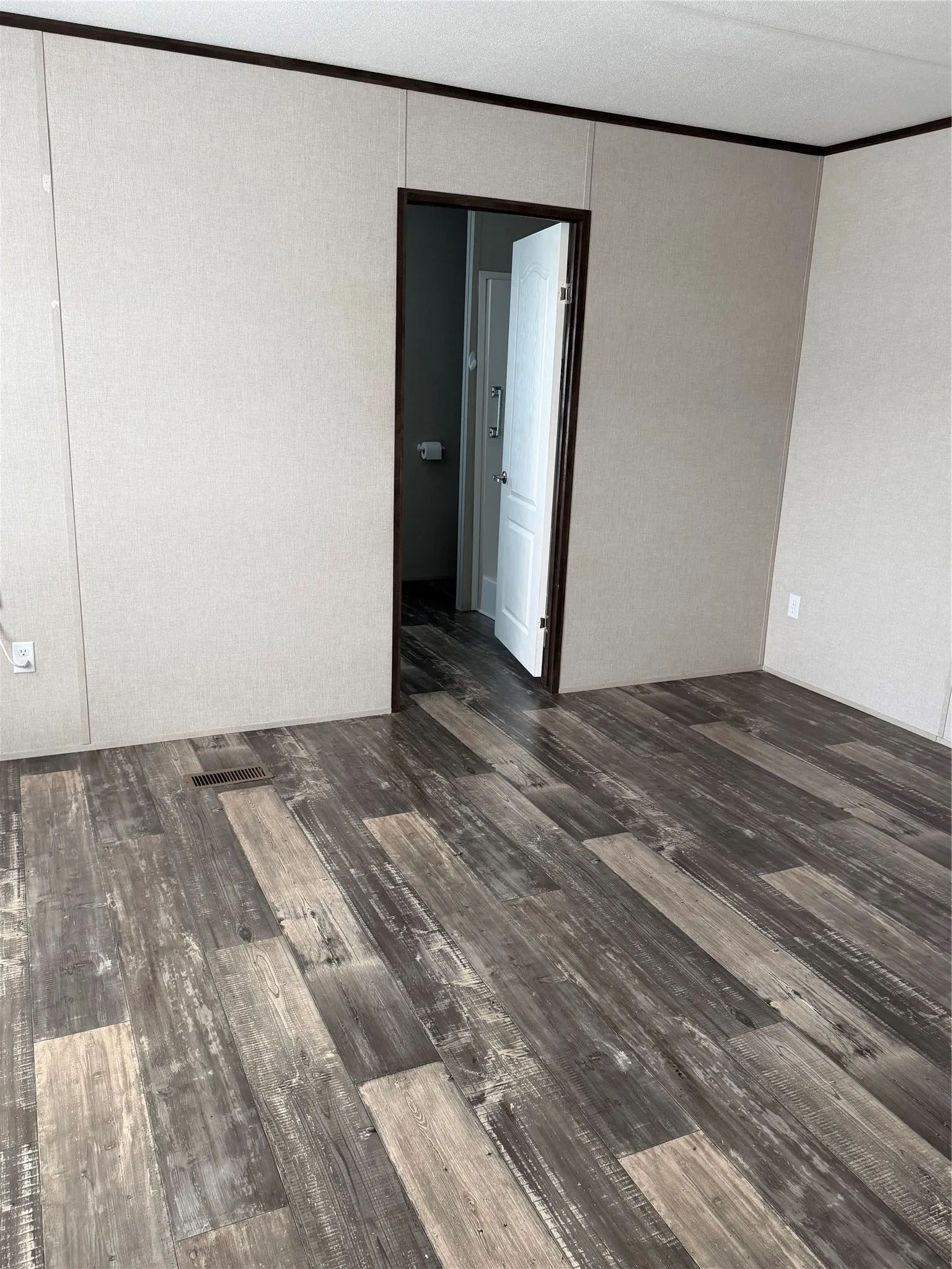 Distressed wood-finish flooring extending into a doorway with contrasting dark trim