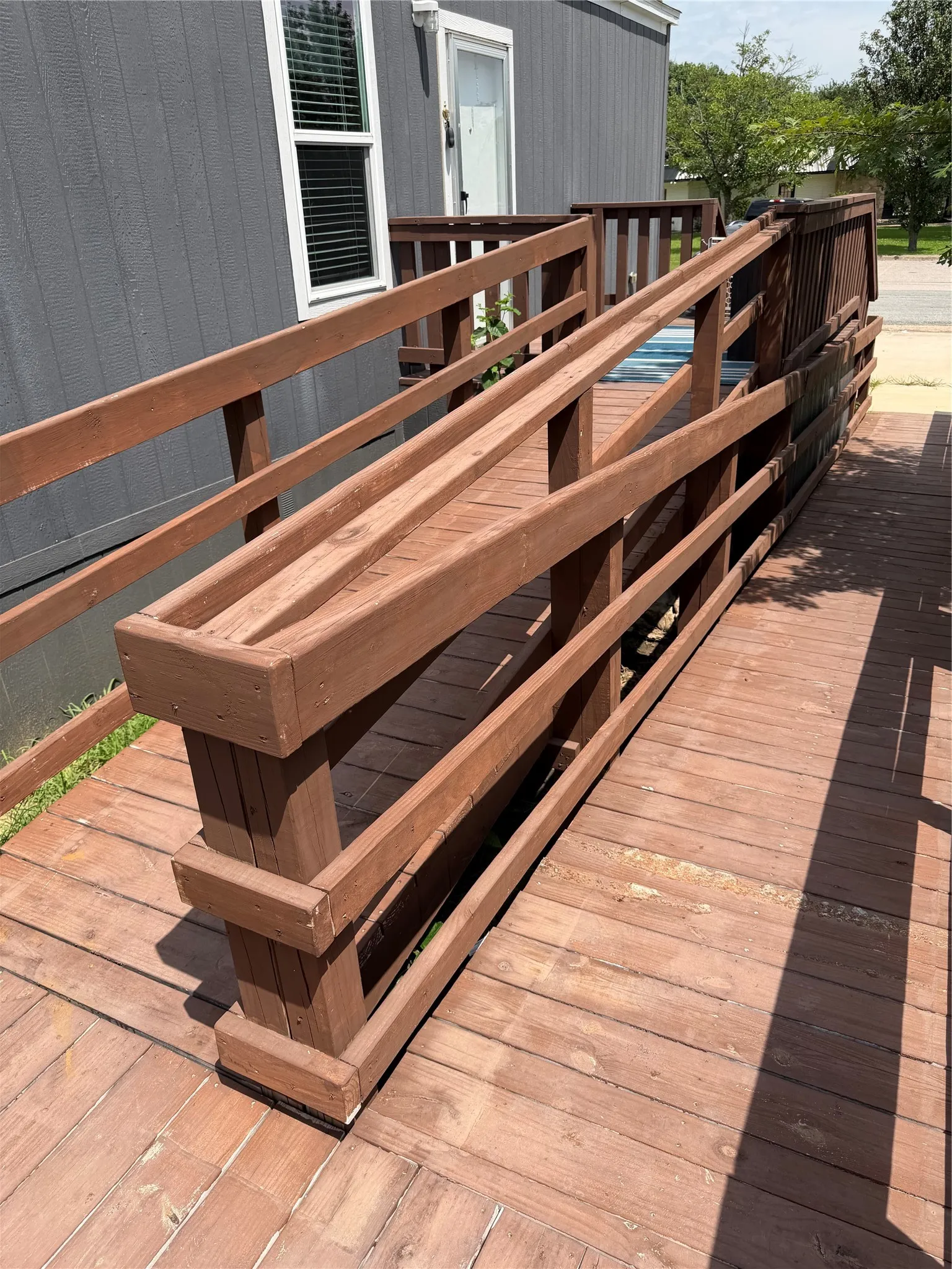 Exterior side entrance featuring a wooden accessibility ramp with railings, connecting to a deck area