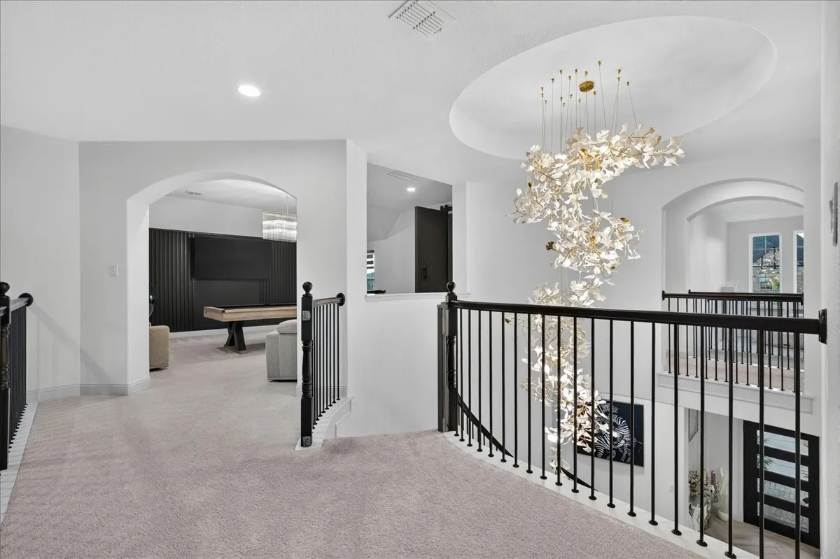 Upper-level landing featuring a grand spiral chandelier suspended from a recessed dome ceiling