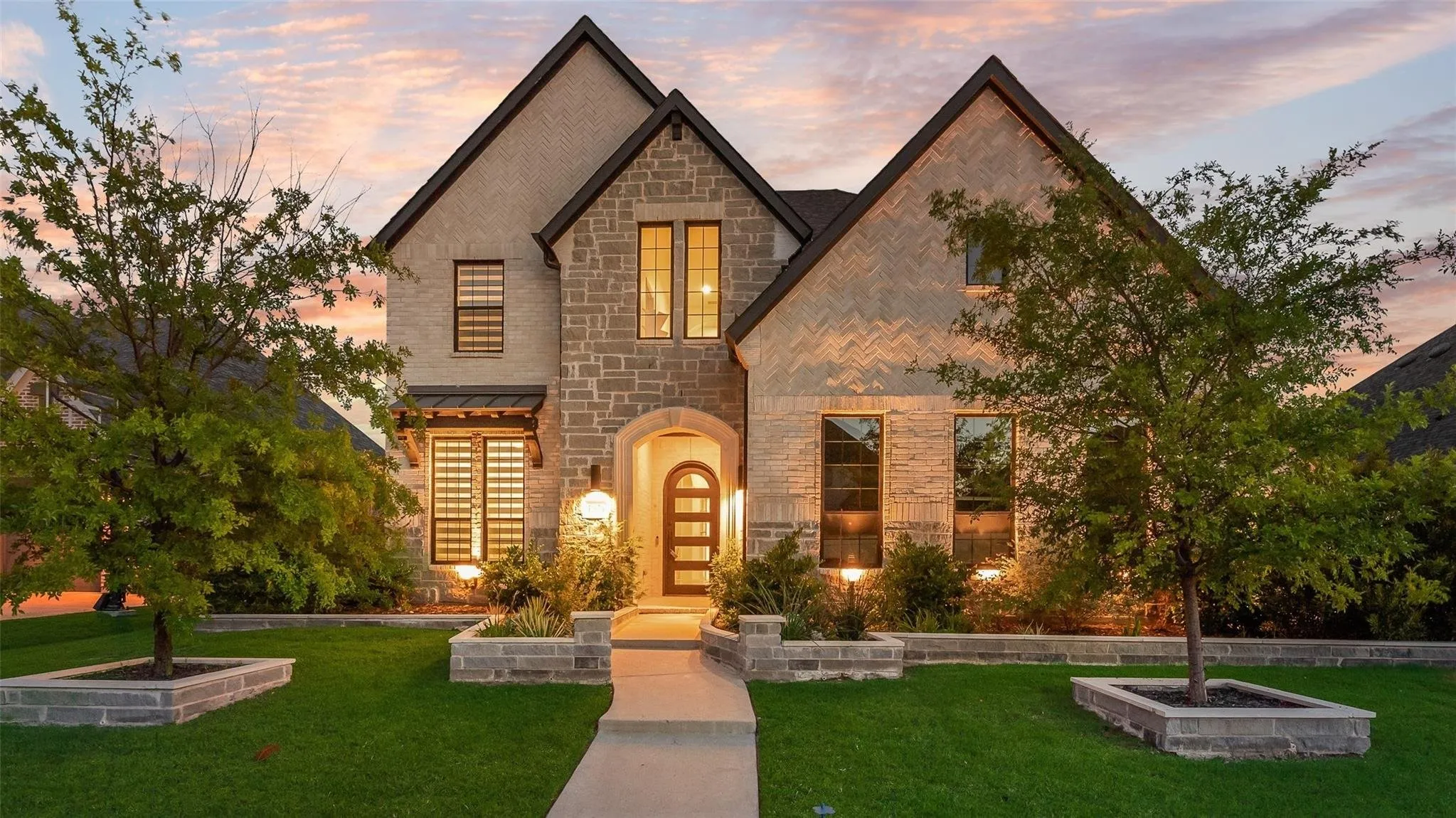 Stone and stucco exterior featuring a prominent arched entryway and dark trim accents