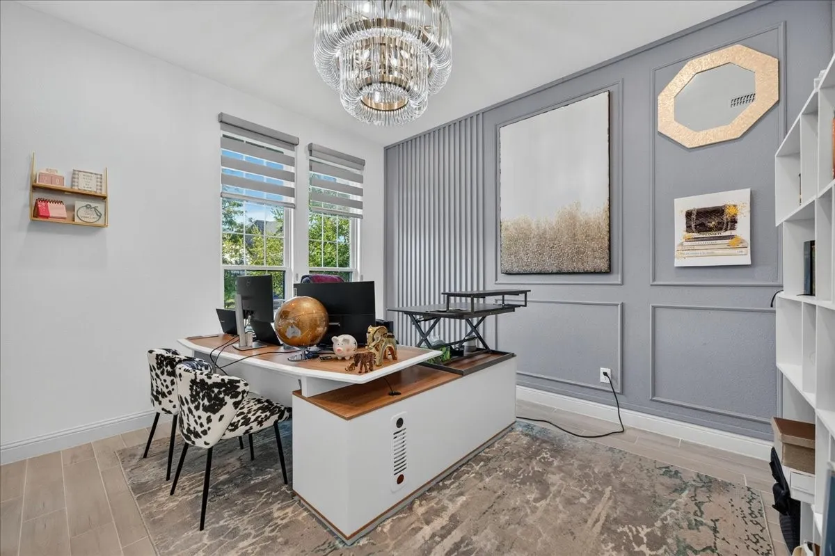 Dedicated office space featuring a contemporary chandelier and light wood-finish flooring