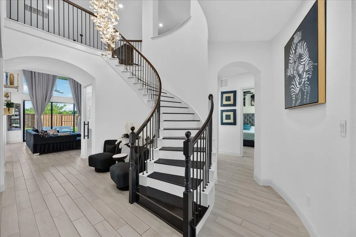 Grand foyer featuring a curved staircase with dark wood treads and wrought iron balusters