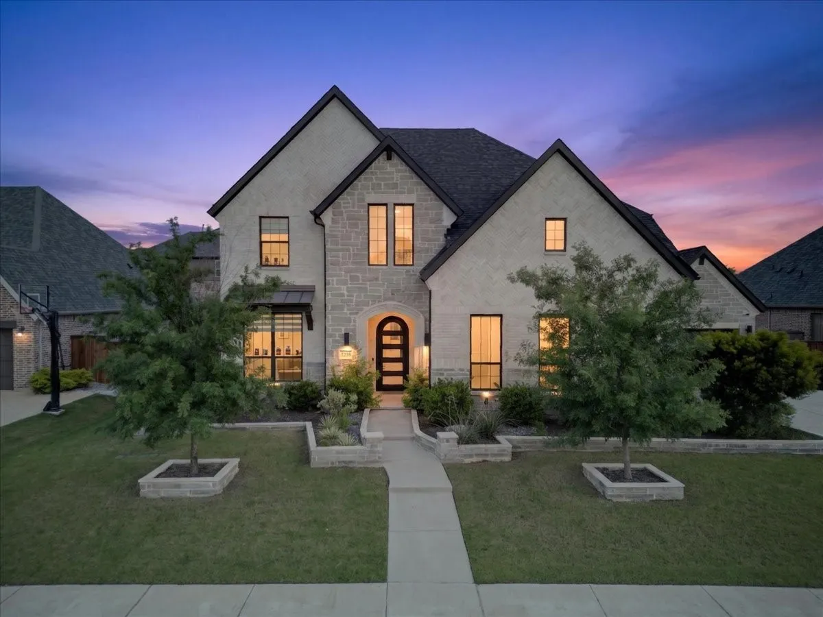 Stately two-story residence featuring a stone and brick façade, dark shingle roof, and multiple gables