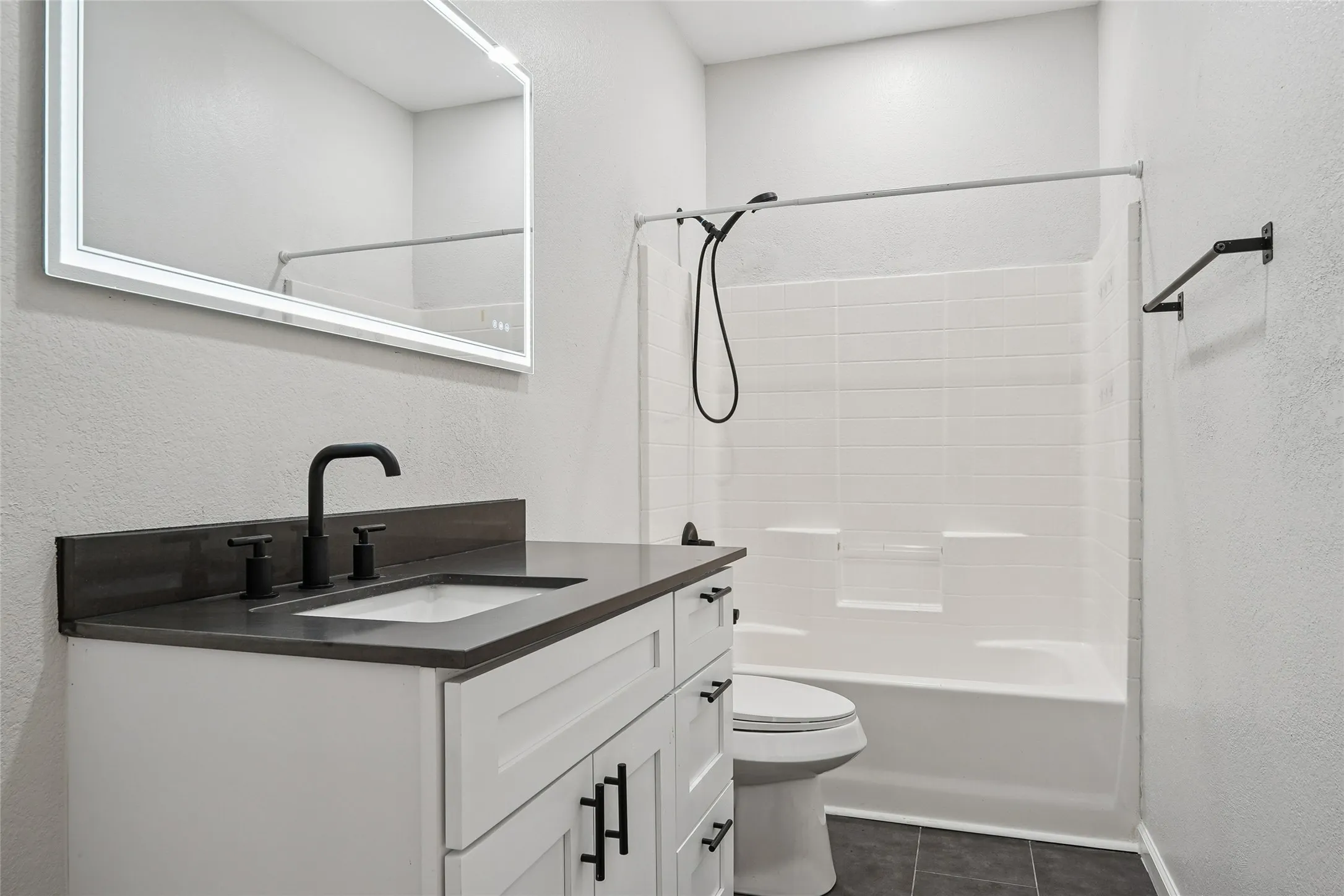 White vanity with matte black hardware, dark countertop, and undermount sink