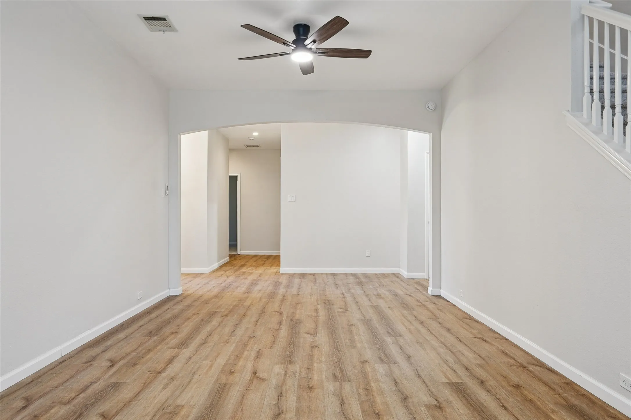 Wood-finish flooring throughout, archway entry, and a ceiling fan