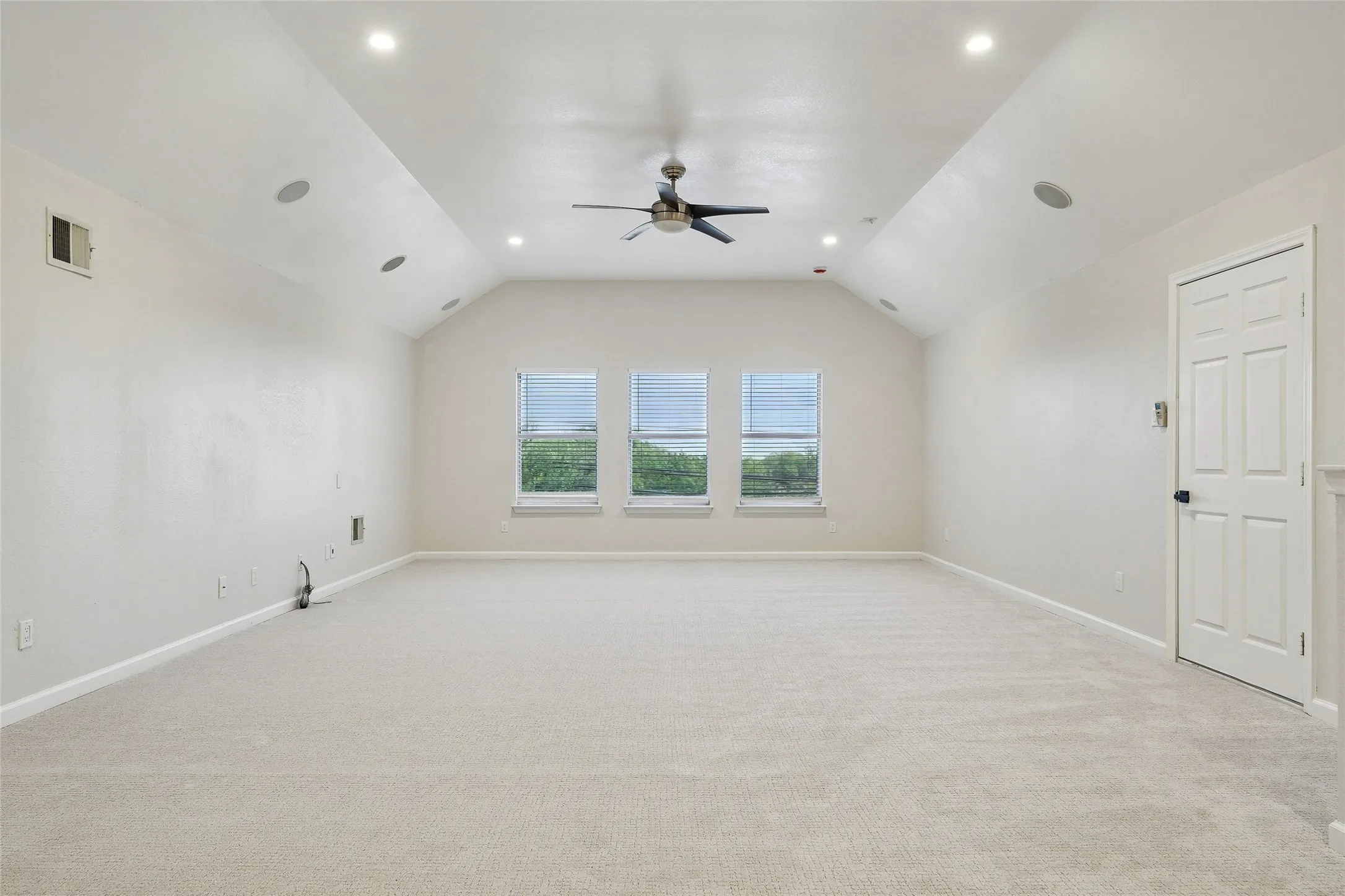 Vaulted ceiling with recessed lighting, ceiling fan, carpet flooring, and three windows with blinds