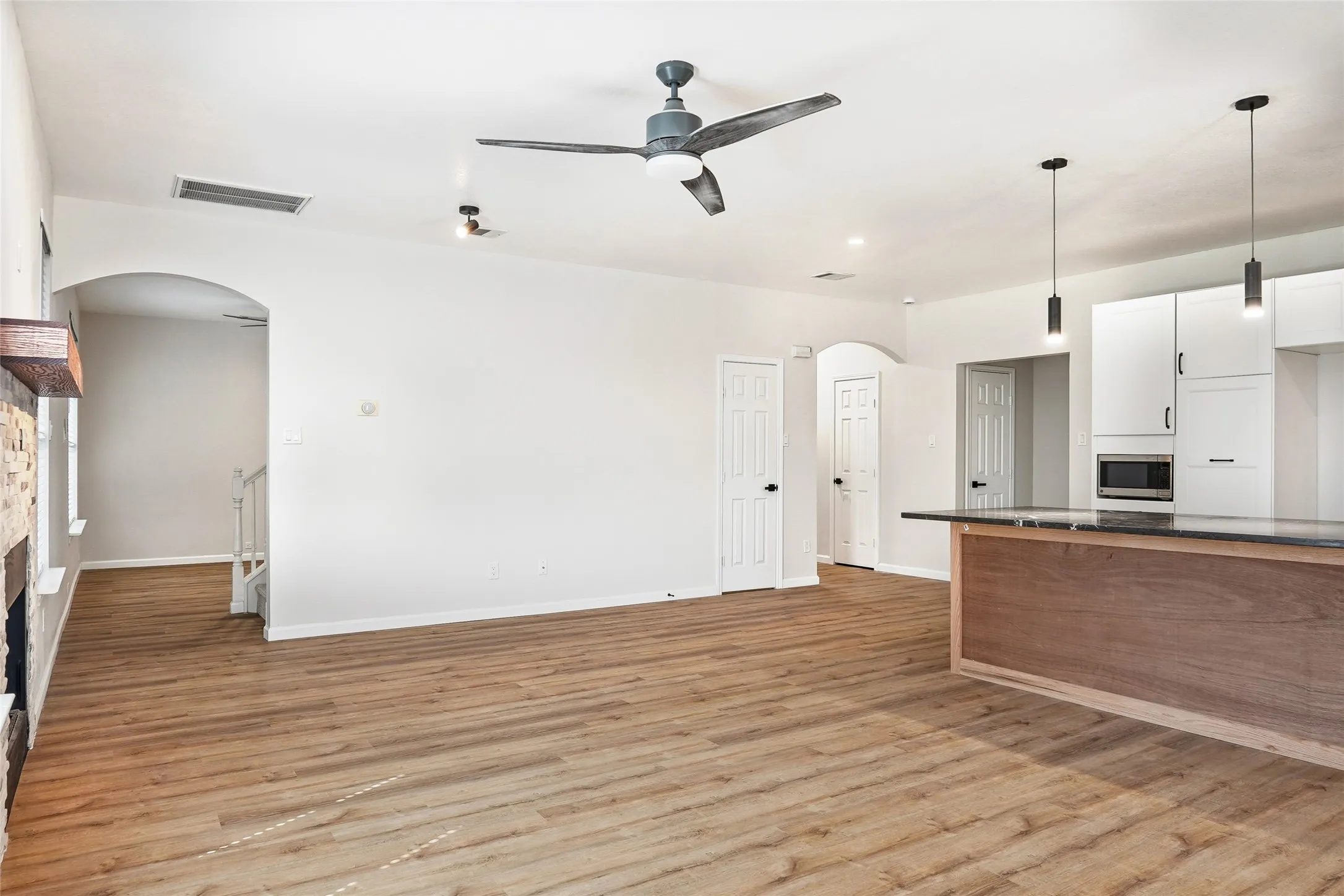 Spacious room featuring wood-finish flooring, a contemporary ceiling fan, and recessed lighting