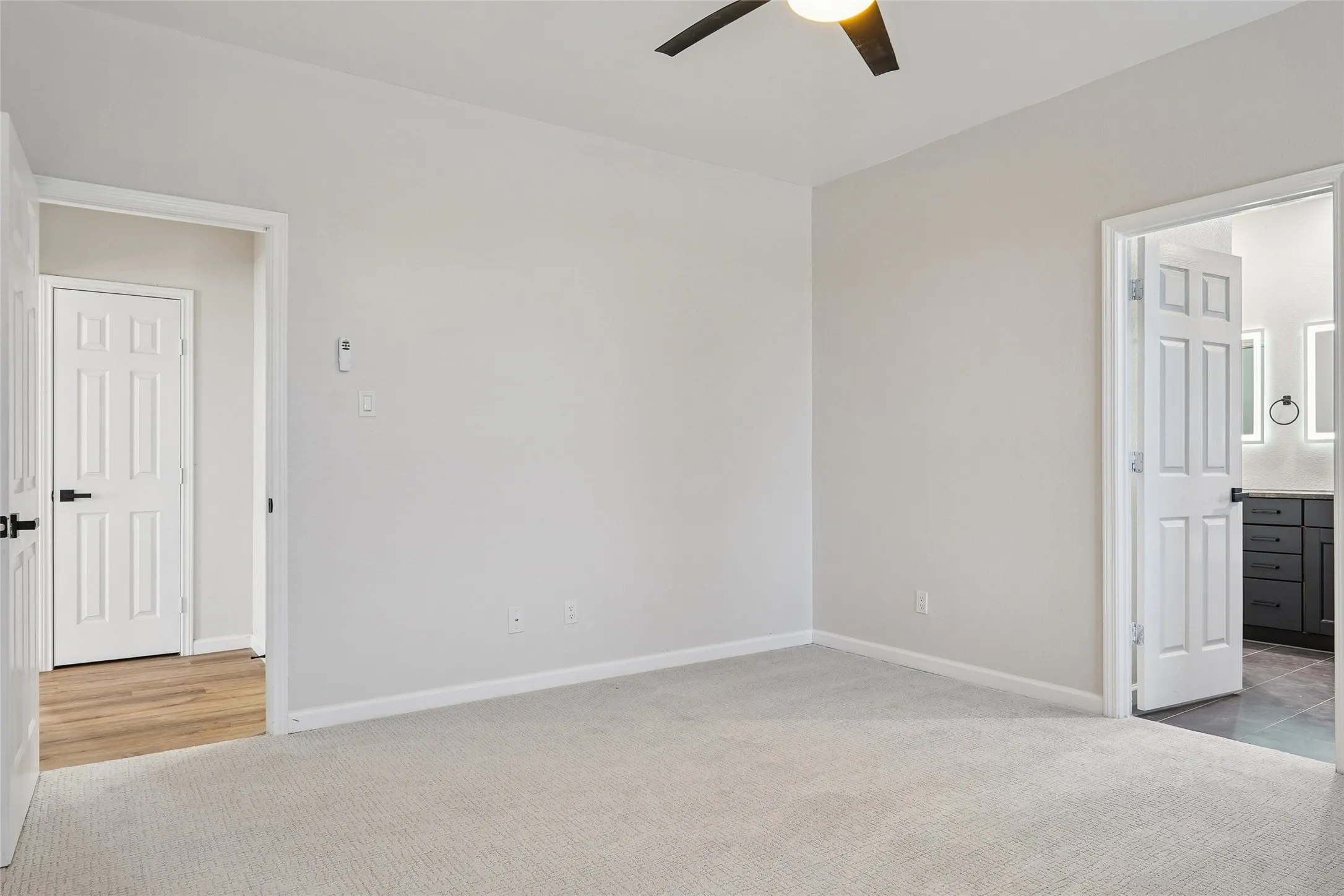Neutral-toned carpeting, ceiling fan with integrated lighting, paneled interior doors, and modern door hardware