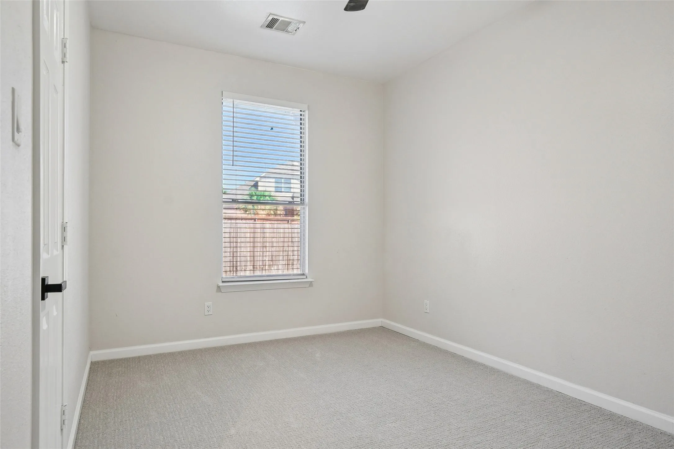 Neutral wall color, light gray carpet, and a window with blinds