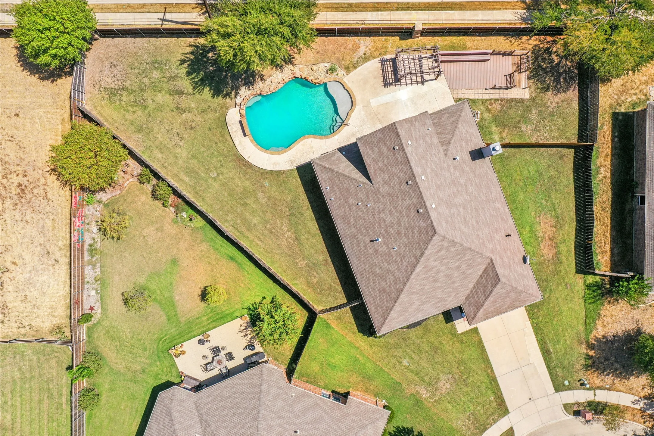 Large lot with a freeform swimming pool, paved pool deck, and a multi-level wood deck