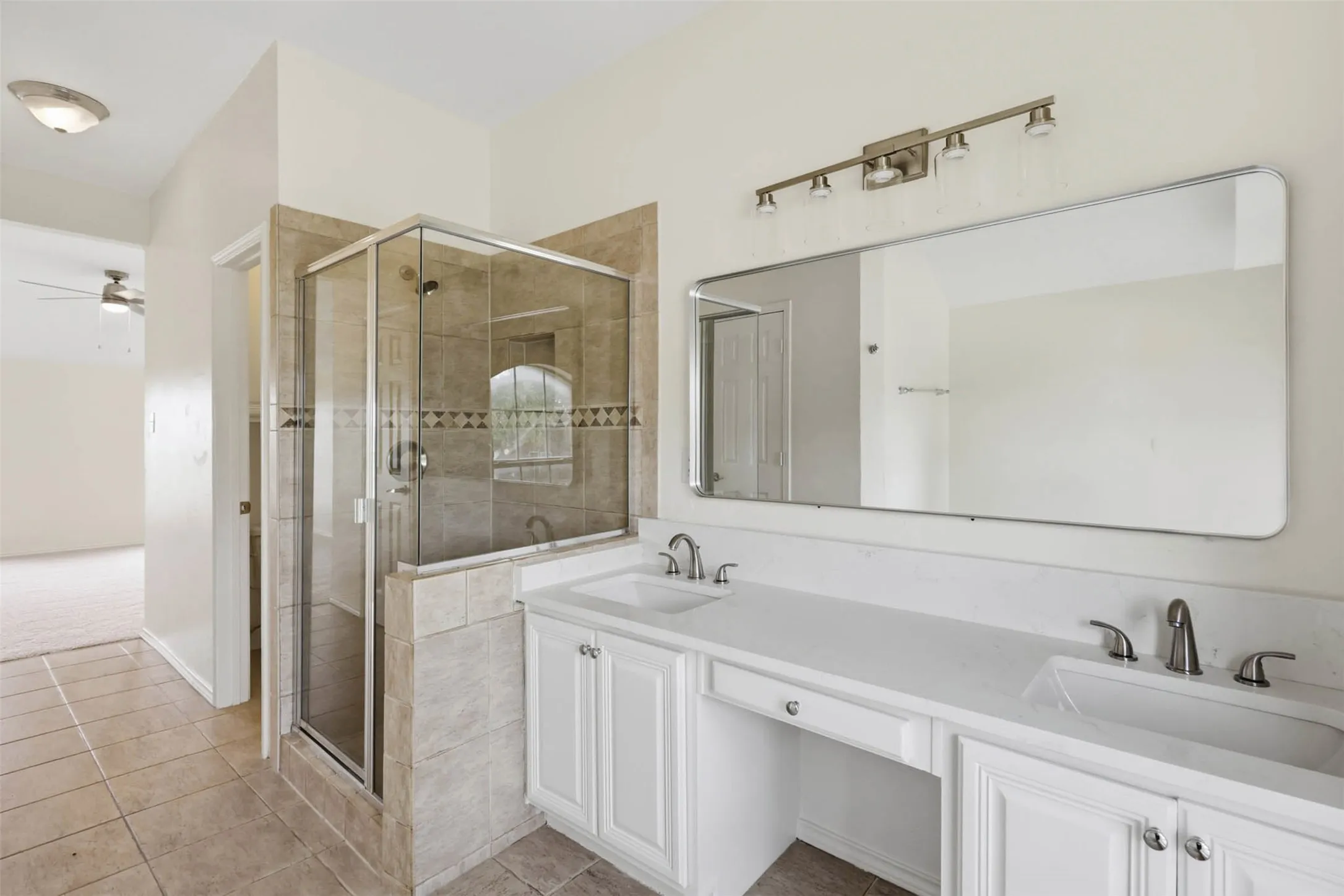 Bathroom featuring a spacious walk-in shower with glass enclosure and neutral tile surround