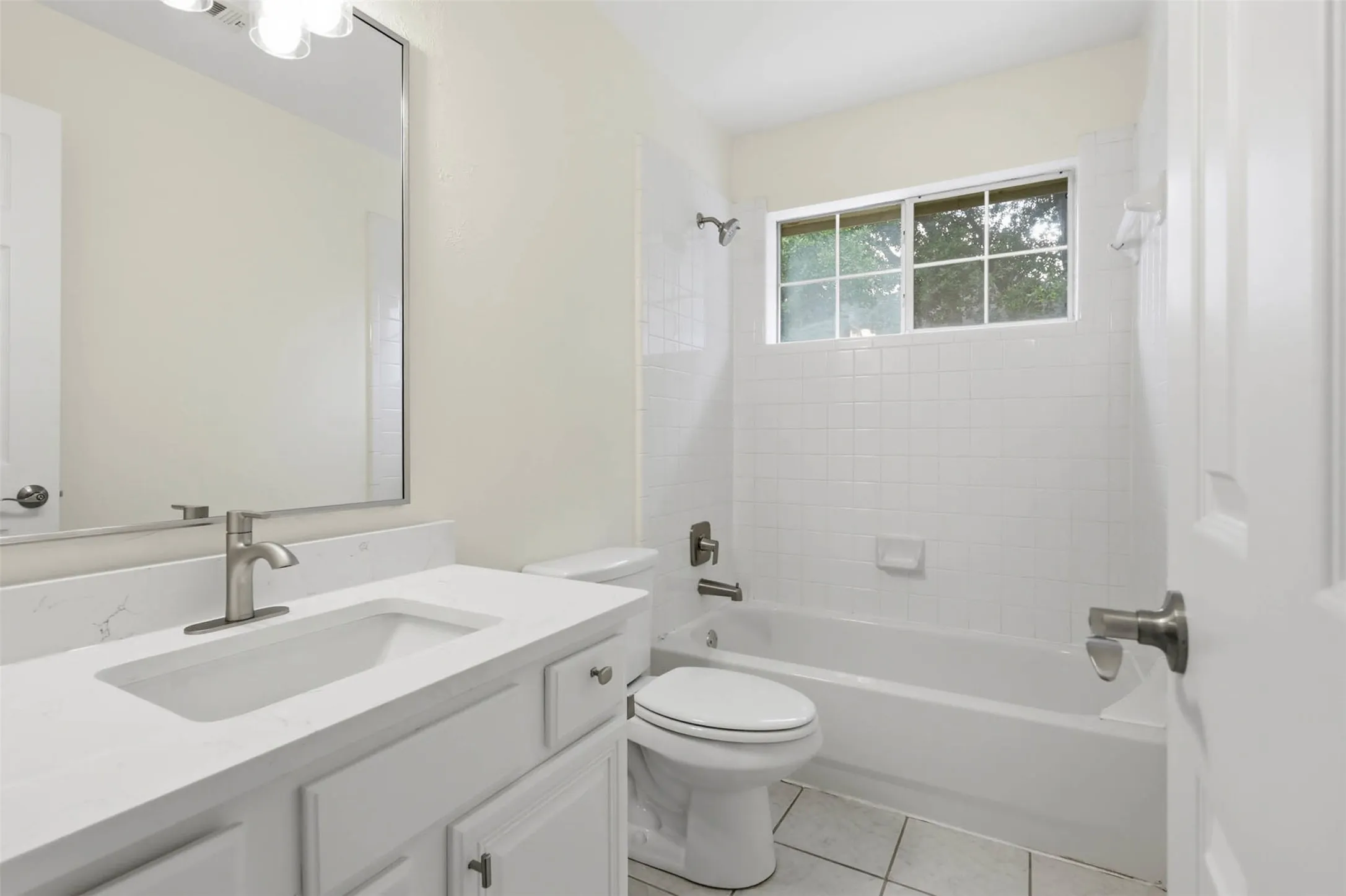 Bathroom featuring a white vanity with an integrated sink, brushed nickel faucet, and a large mirror