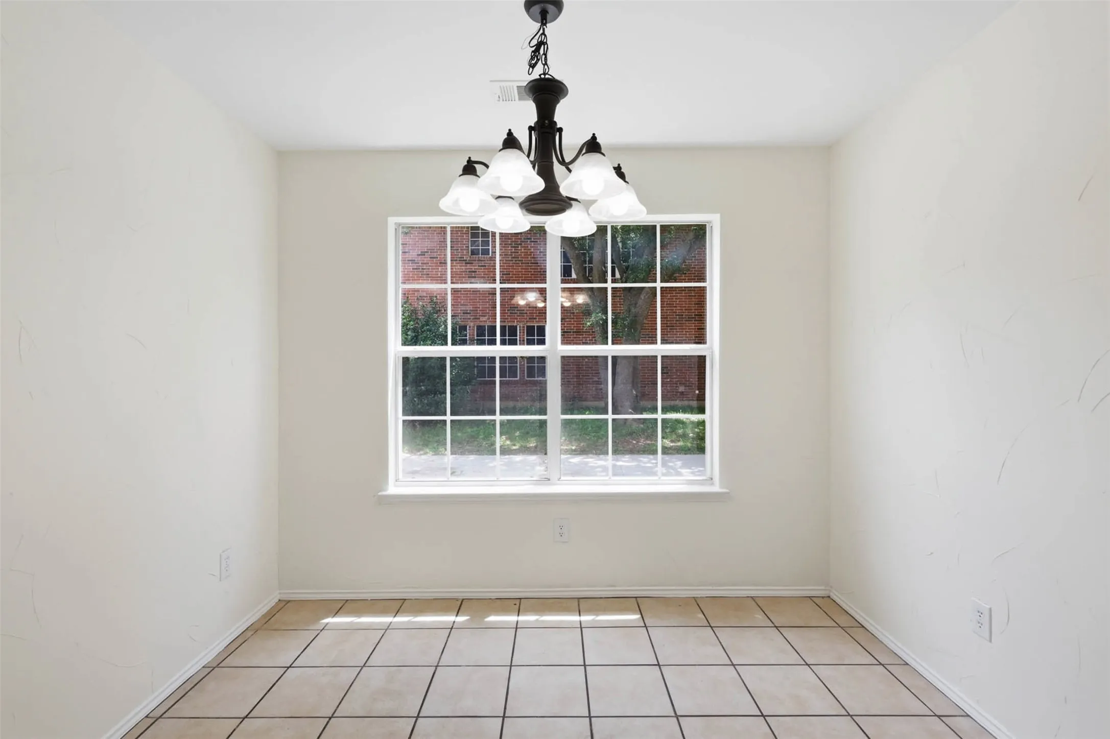 Room featuring neutral-toned walls, tile flooring, and a central window with gridded panes
