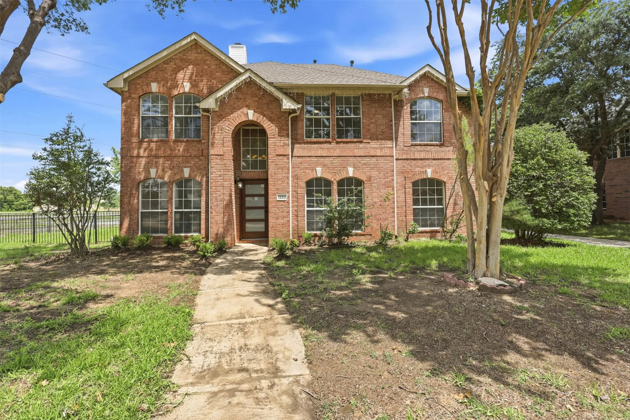 Brick facade residence with a prominent arched entry, multiple arched windows, and a contemporary front door with vertical glass panels