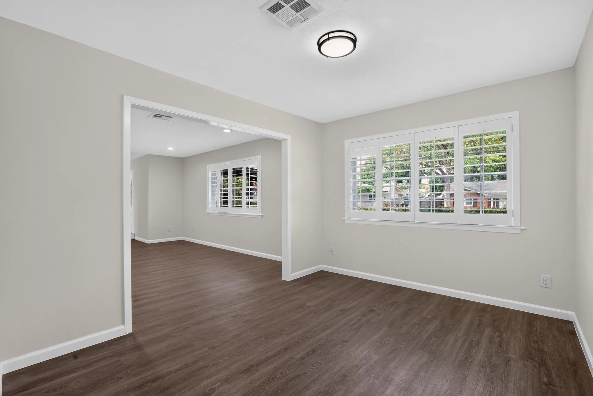 Spacious interior featuring wood-finish flooring, white baseboards, and neutral wall tones