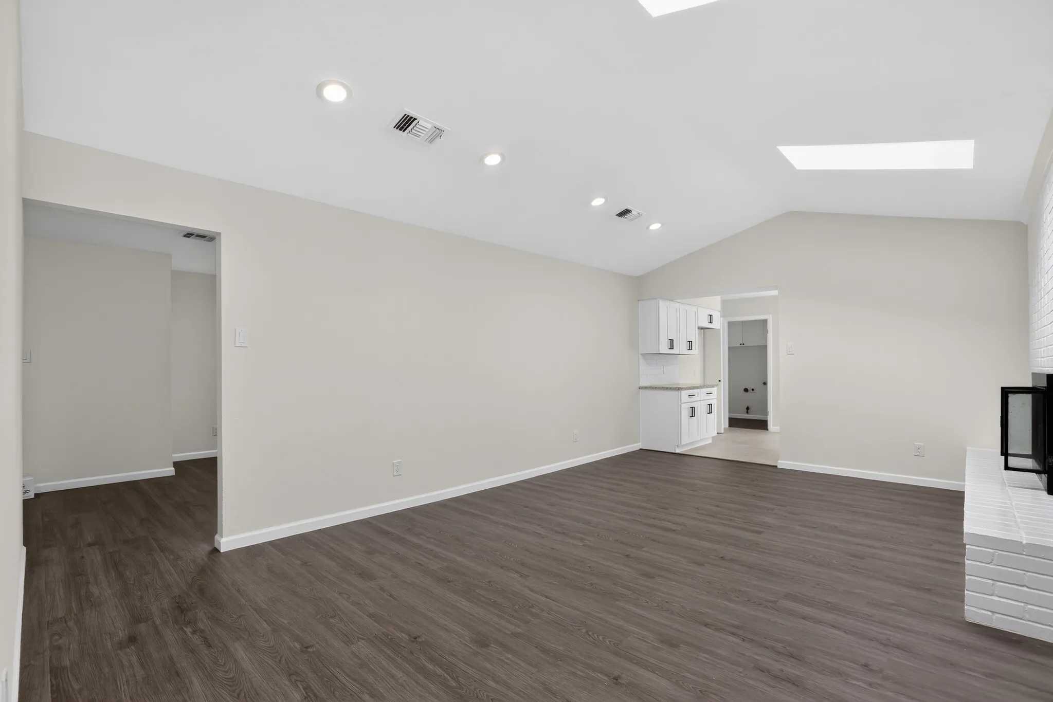 Vaulted ceiling featuring recessed lighting and skylights, complemented by wood-finish flooring
