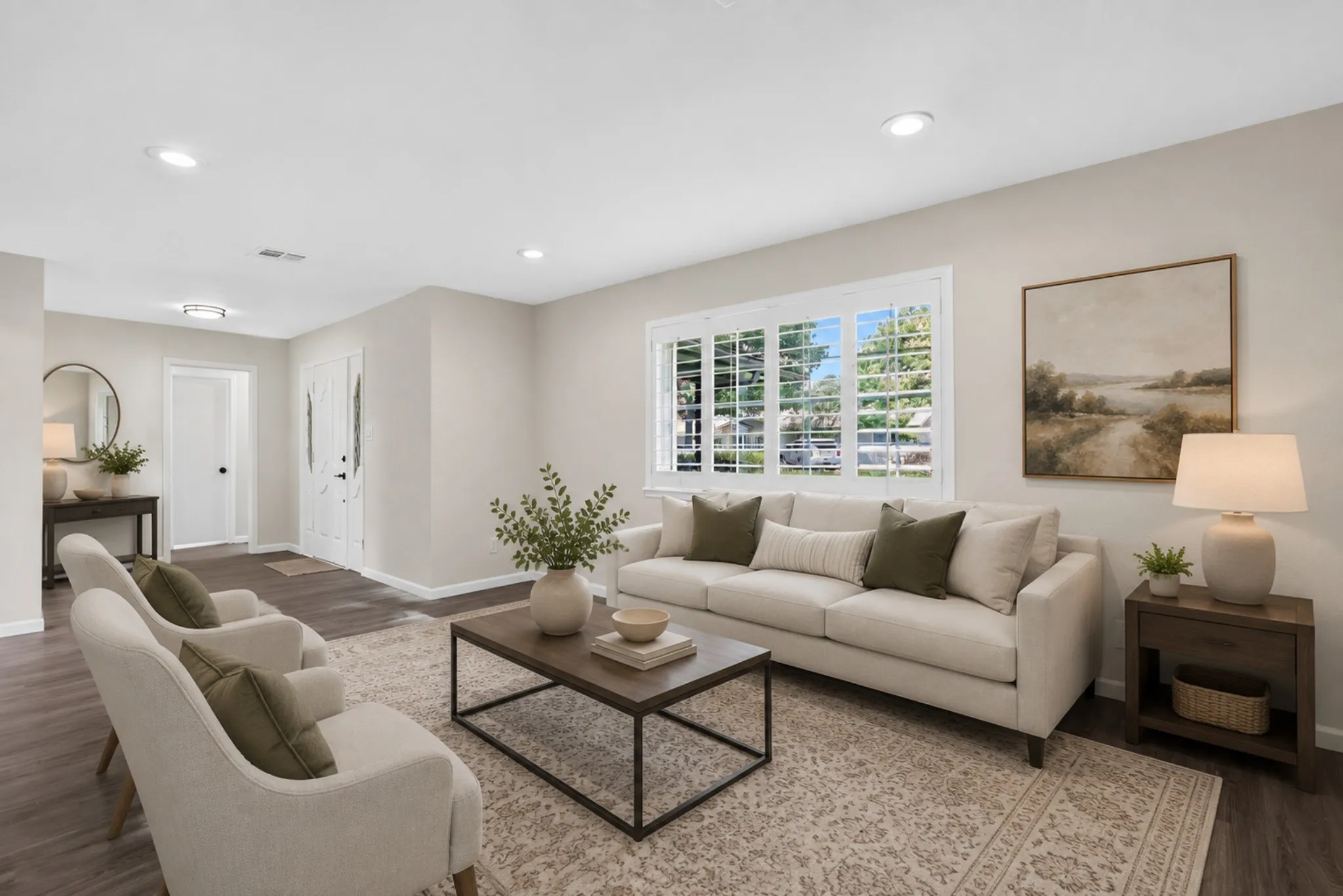 Spacious living area featuring wood-finish flooring, recessed lighting, and a large window with plantation shutters