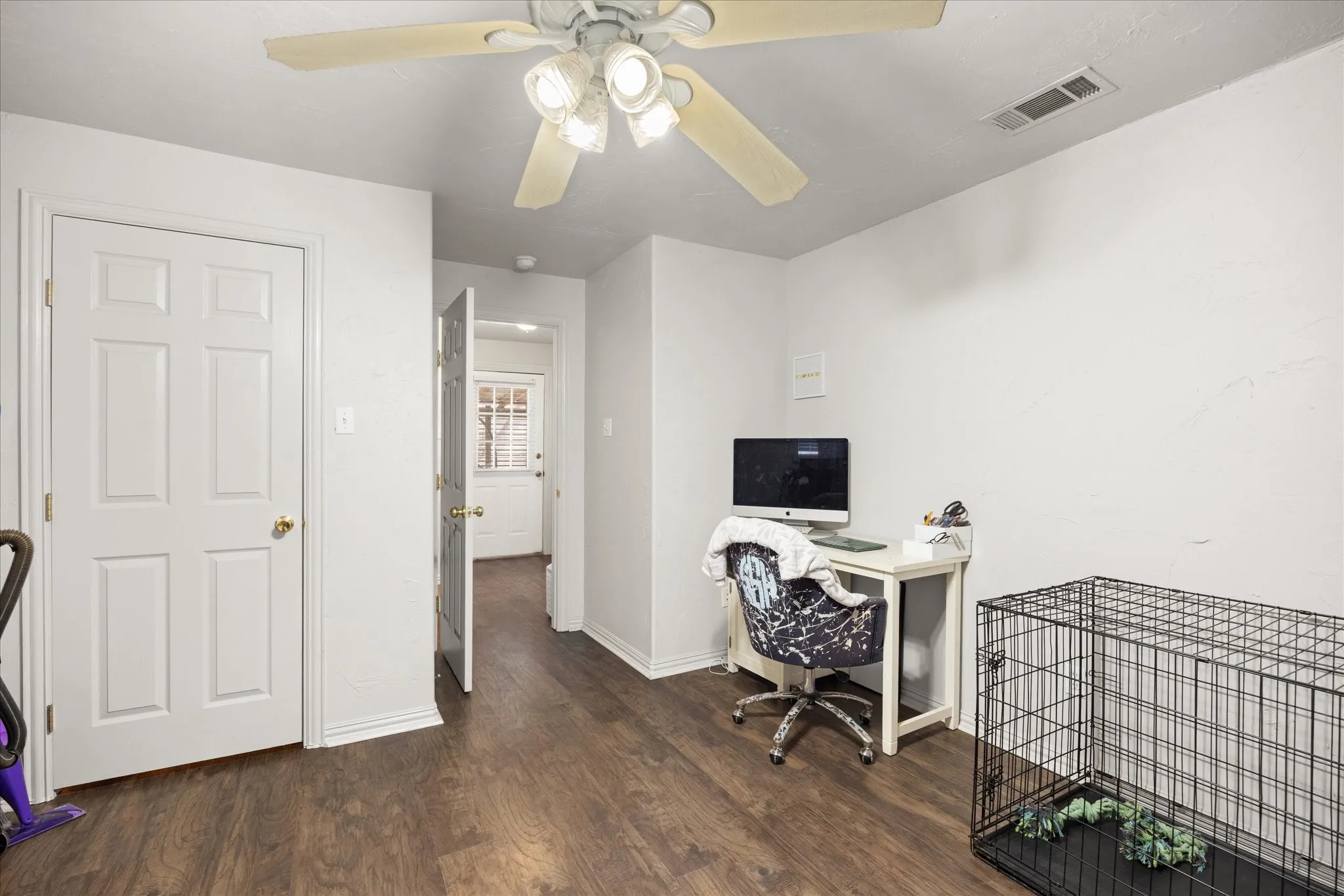 Spacious room featuring wood-finish flooring, white walls, and a ceiling fan with integrated lighting