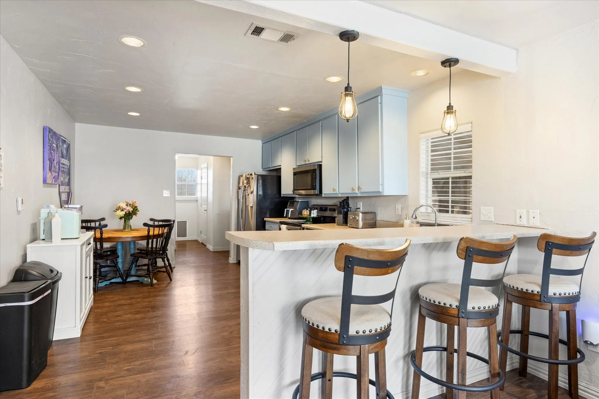 Kitchen with light blue cabinetry, integrated appliances, and a breakfast bar with pendant​​‌​​​​‌​​‌‌​‌‌​​​‌‌​‌​‌​‌​​​‌​​ lighting