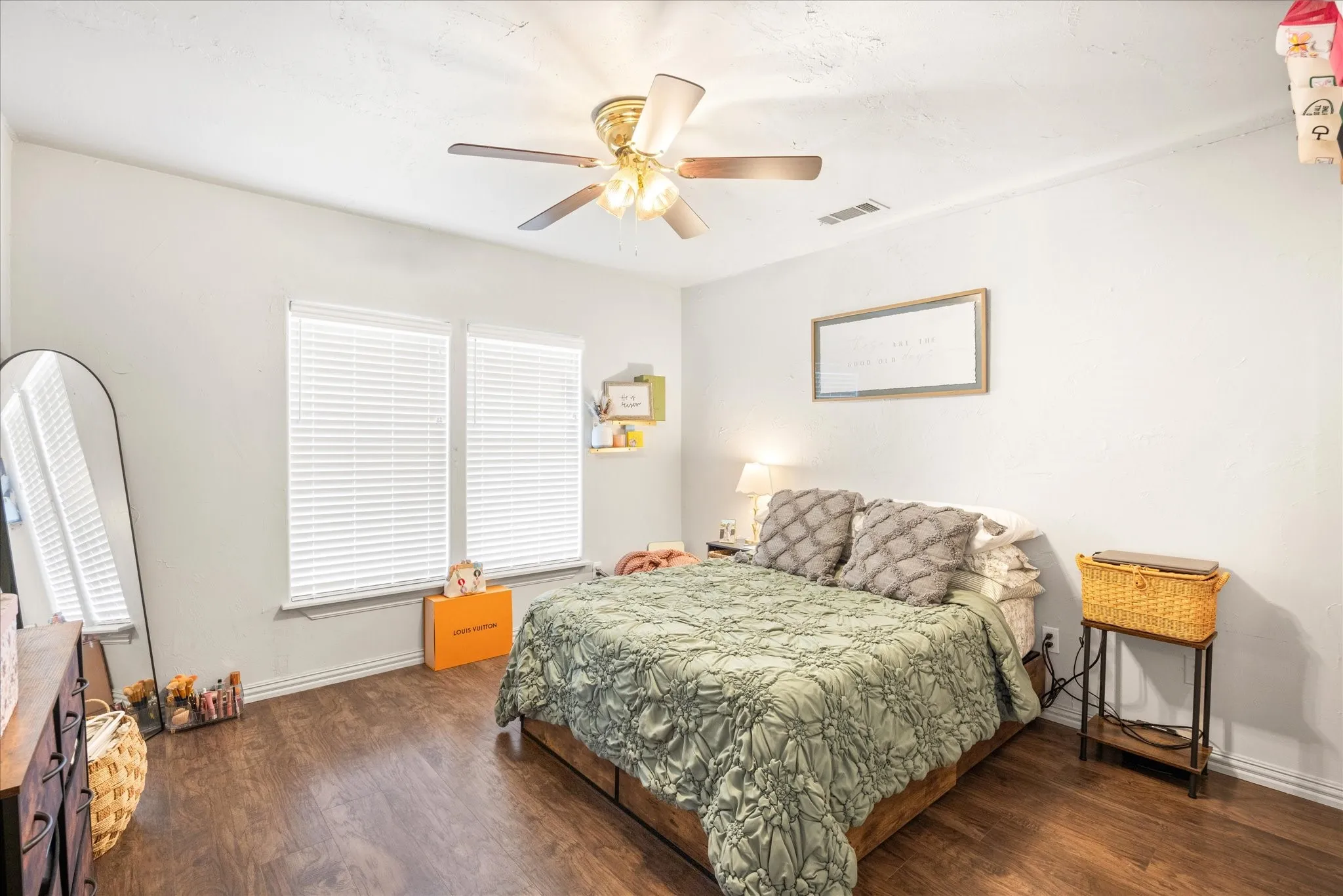 Bedroom featuring wood-finish flooring, two large windows with blinds, a ceiling fan with integrated lighting, and neutral wall tones