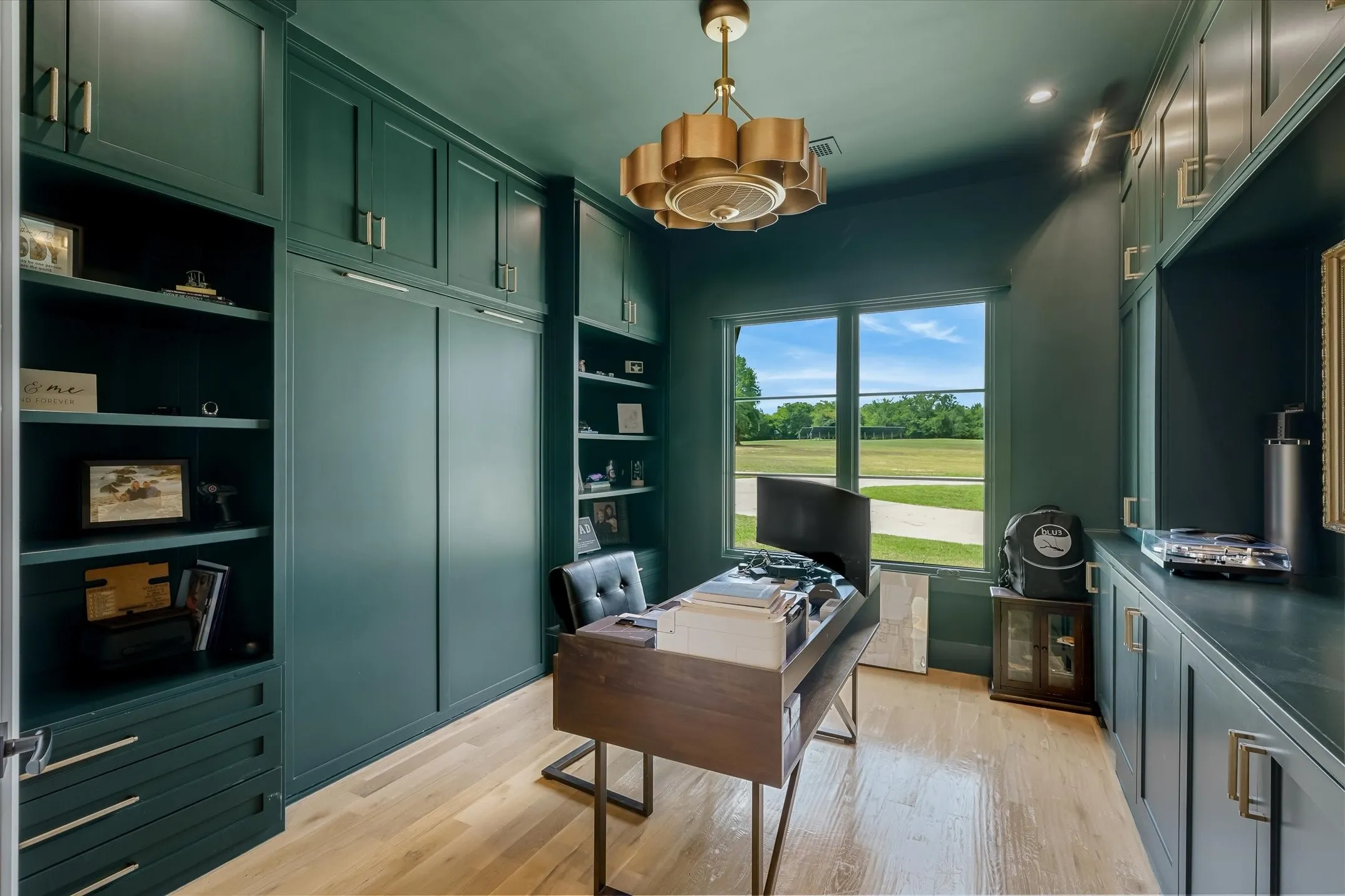 Dedicated office space with extensive built-in cabinetry, integrated shelving, and light wood-finish flooring