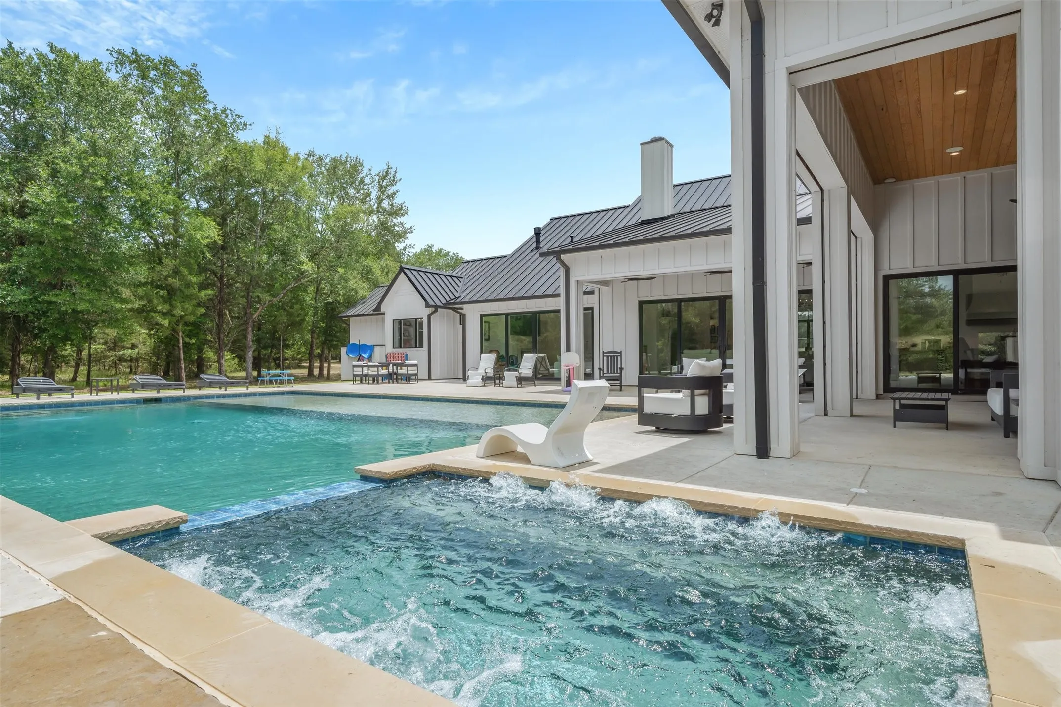 Outdoor living space featuring a heated swimming pool, separate spa, and a covered patio with a wood-paneled ceiling