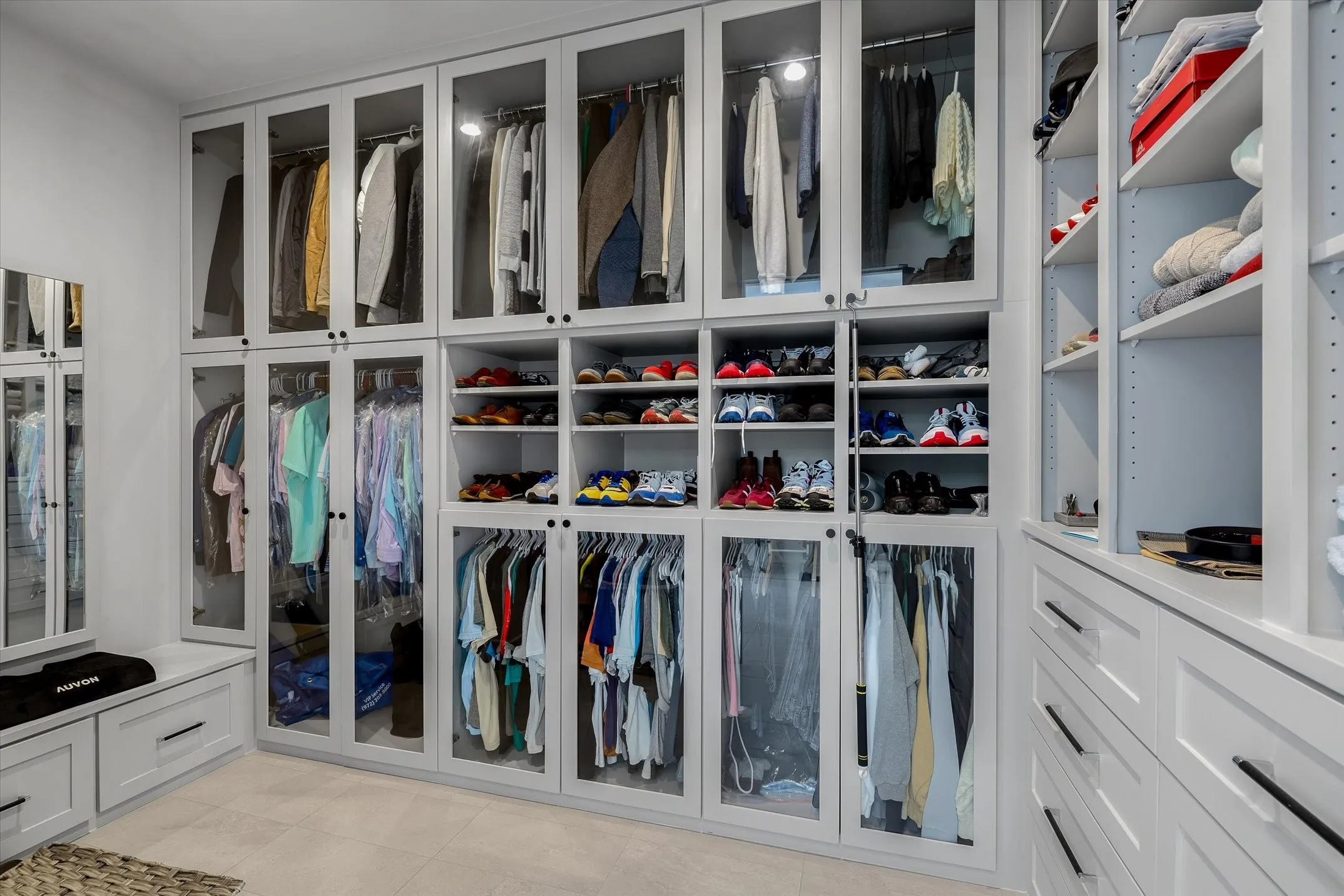 Custom closet system featuring built-in cabinetry with glass-front doors, open shelving, and integrated lighting
