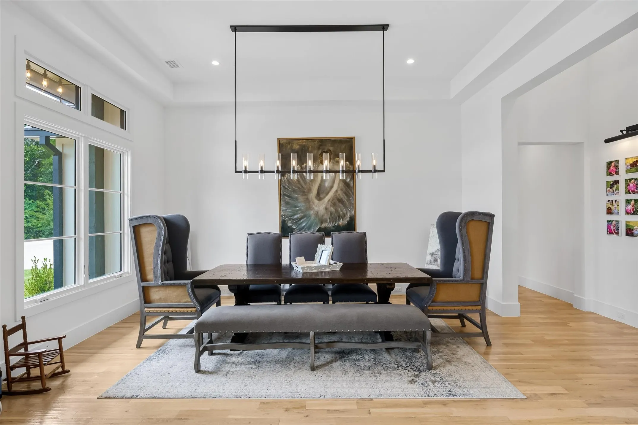 Formal dining area featuring light wood-finish flooring, a contemporary linear chandelier, recessed lighting, expansive windows, and a tray ceiling