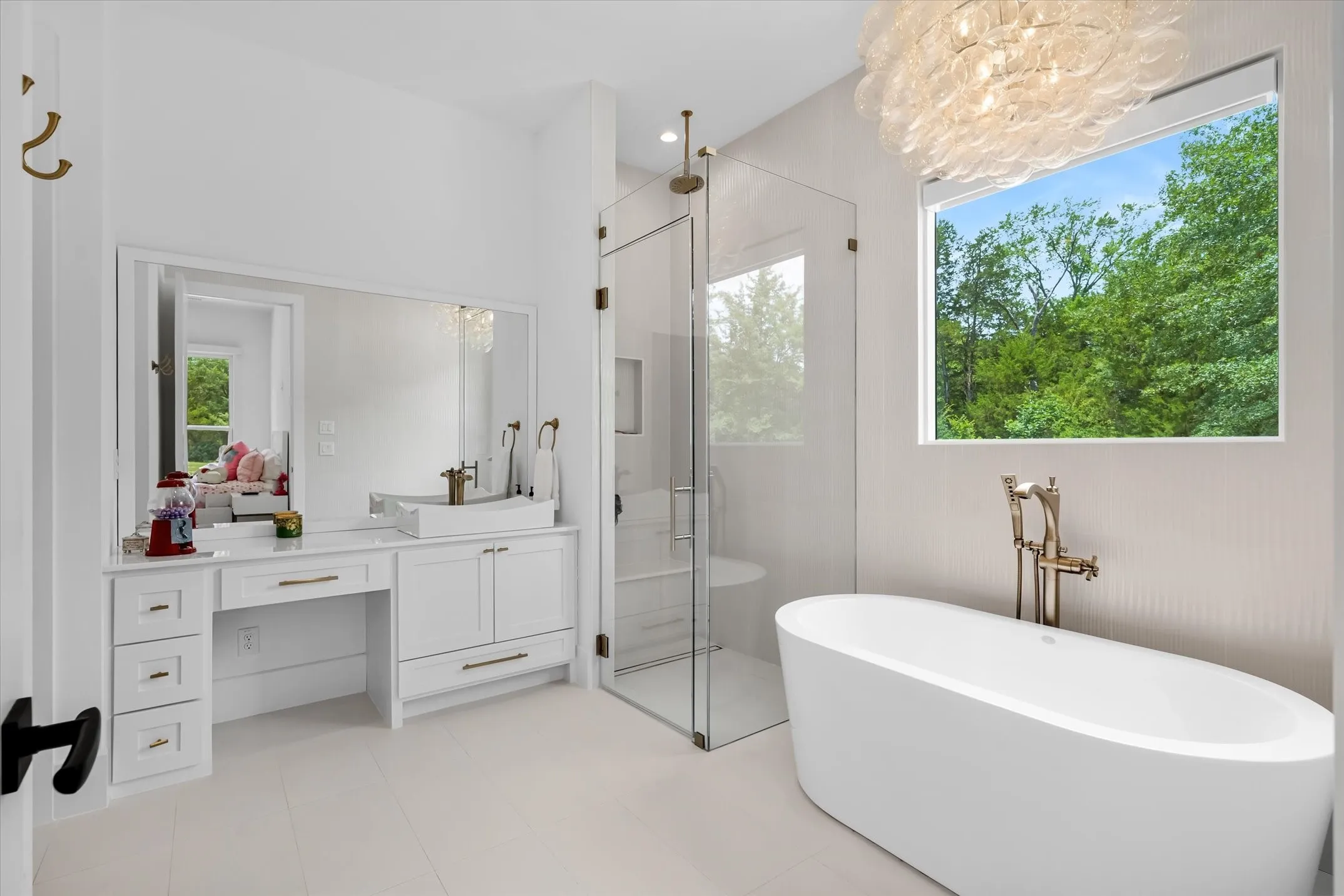 Bathroom featuring a freestanding soaking tub with floor-mounted fixtures, a frameless glass shower enclosure, and an elongated vanity with an integrated basin sink