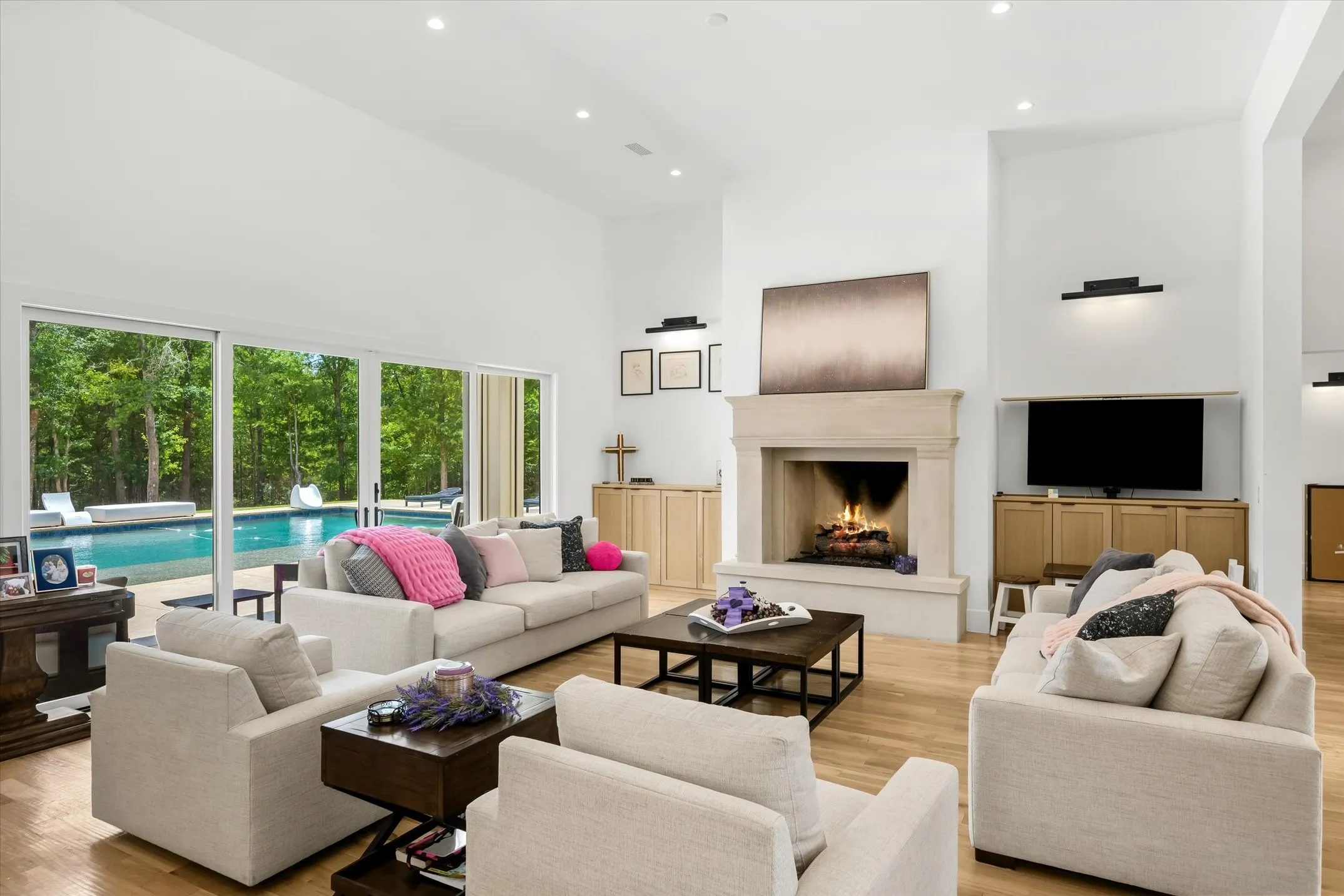 Spacious living area featuring high ceilings, wood-finish flooring, and a stone fireplace