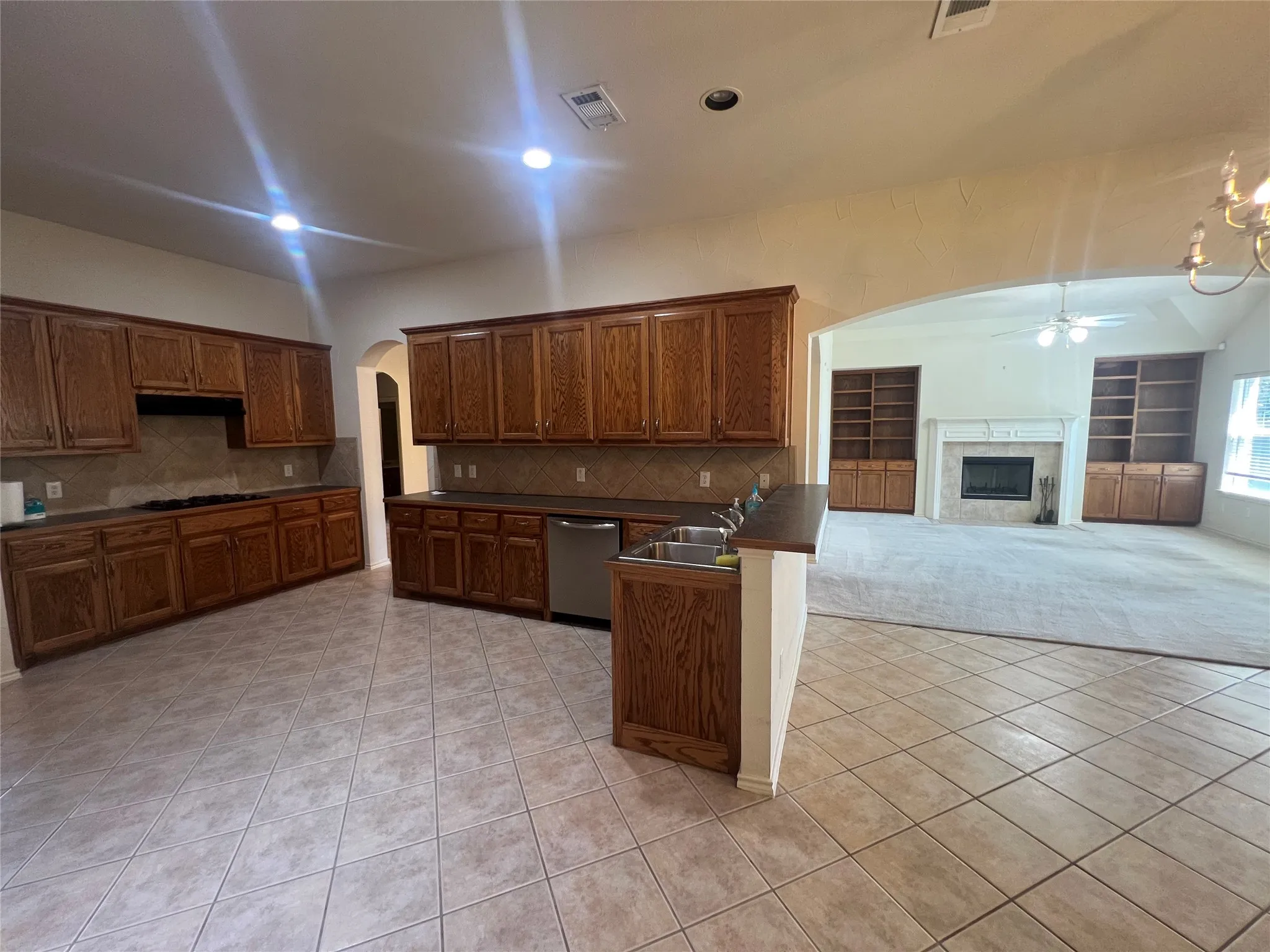 Expansive kitchen featuring wood cabinetry, tile flooring, a gas range, and a double basin sink
